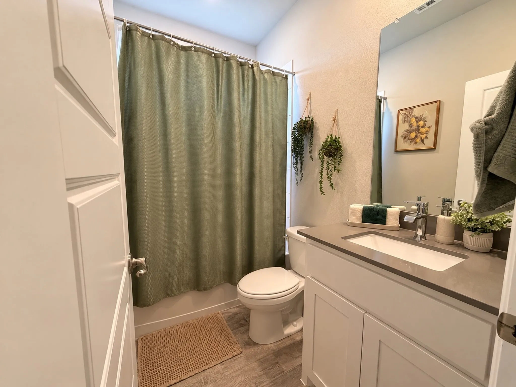 White vanity with a rectangular sink, polished chrome faucet, and gray countertop