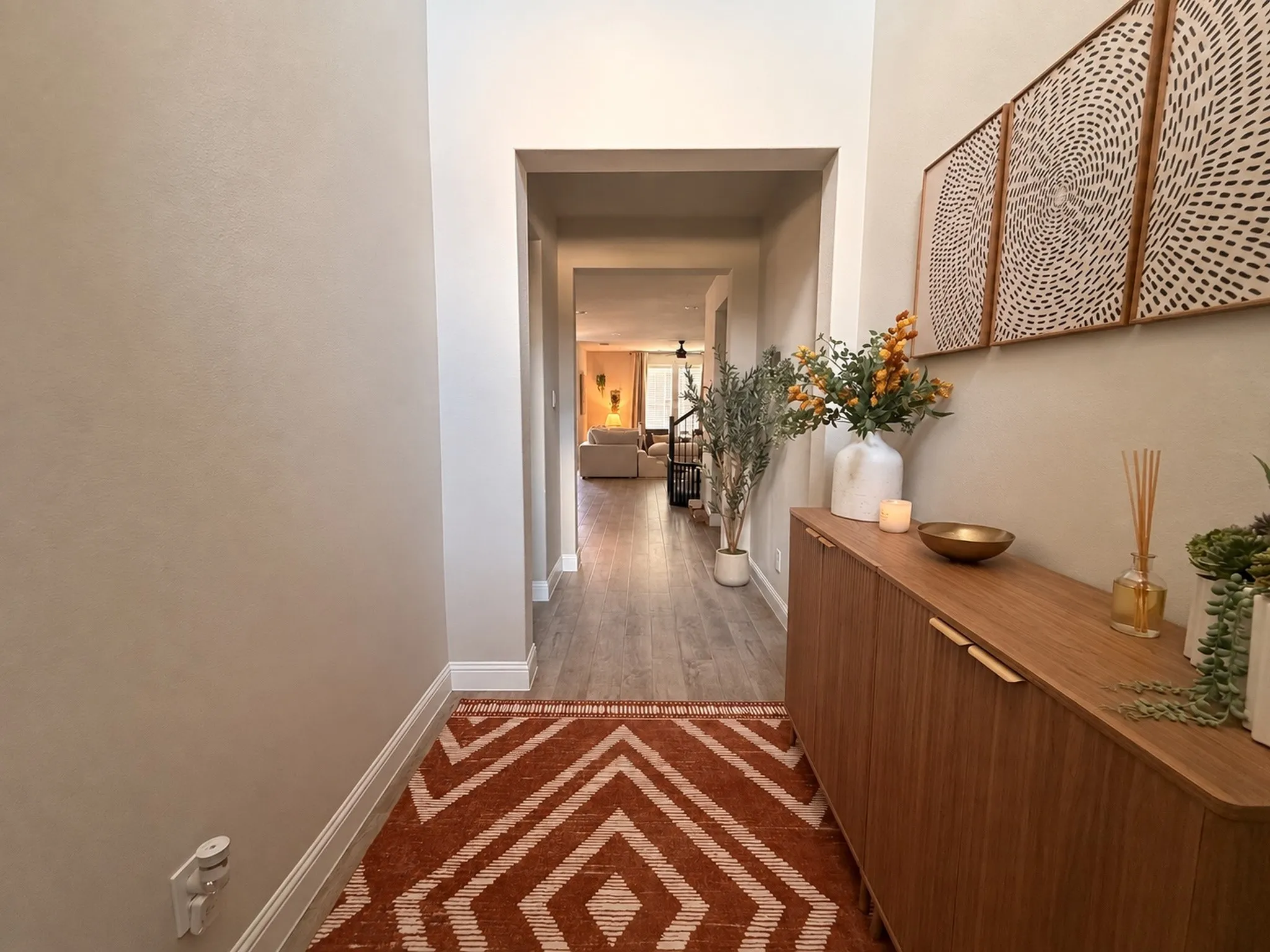 Hardwood-look flooring throughout, recessed ceiling, and a built-in wood-finish console with integrated handles