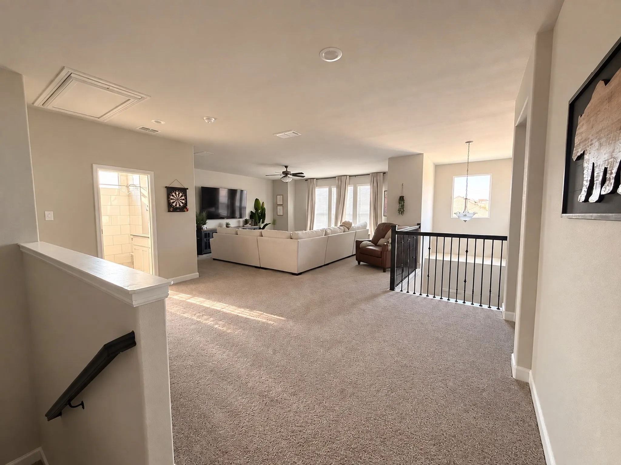 Spacious carpeted loft with recessed lighting, ceiling fan, and iron baluster railing