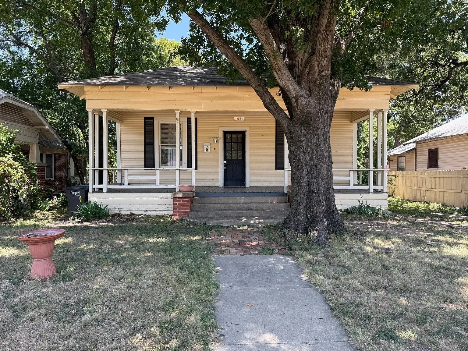 Covered front porch with white columns, brick steps, and a sidewalk leading to the entrance