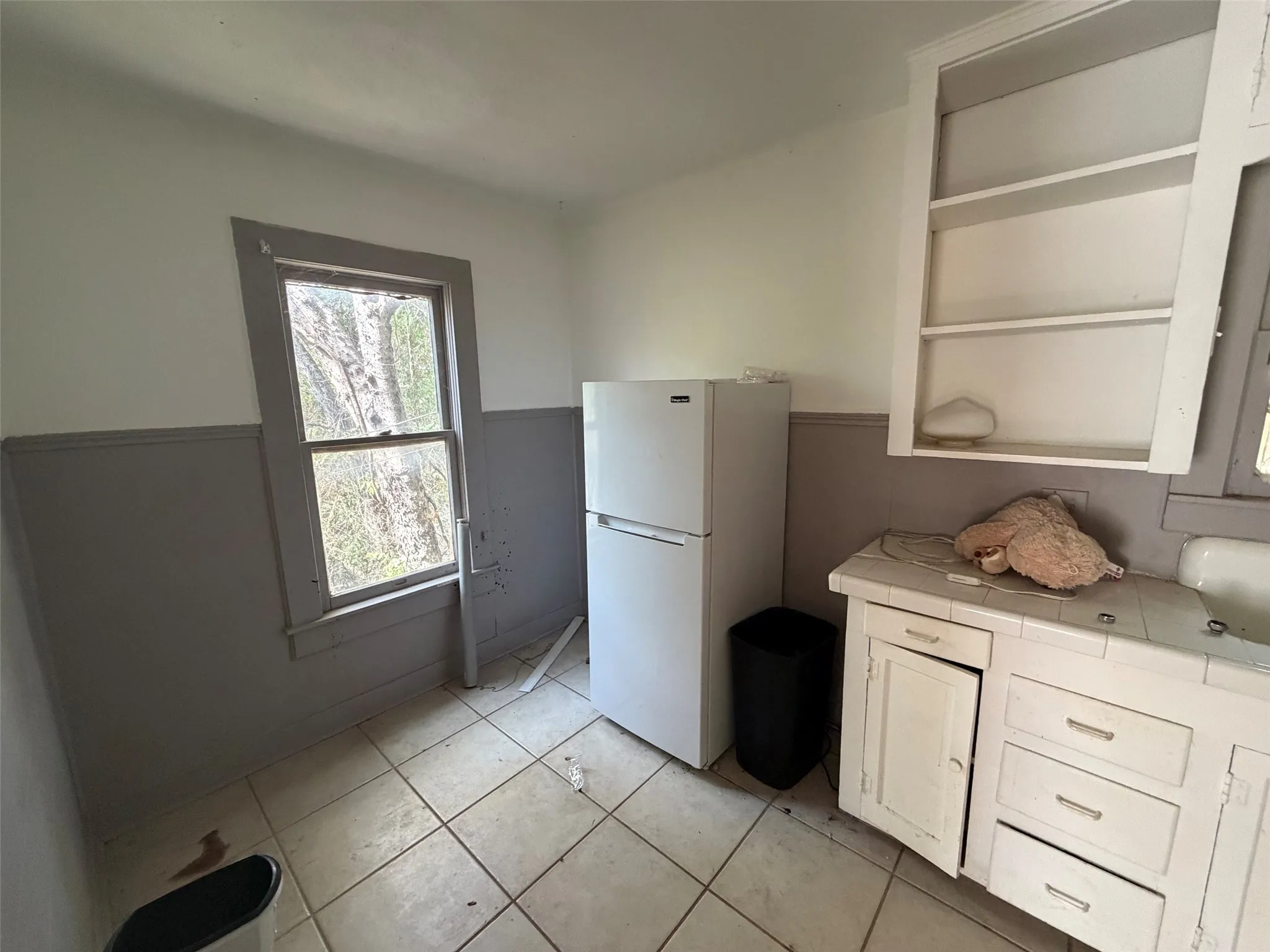 White tile flooring, white cabinetry, a single window, and a white sink basin