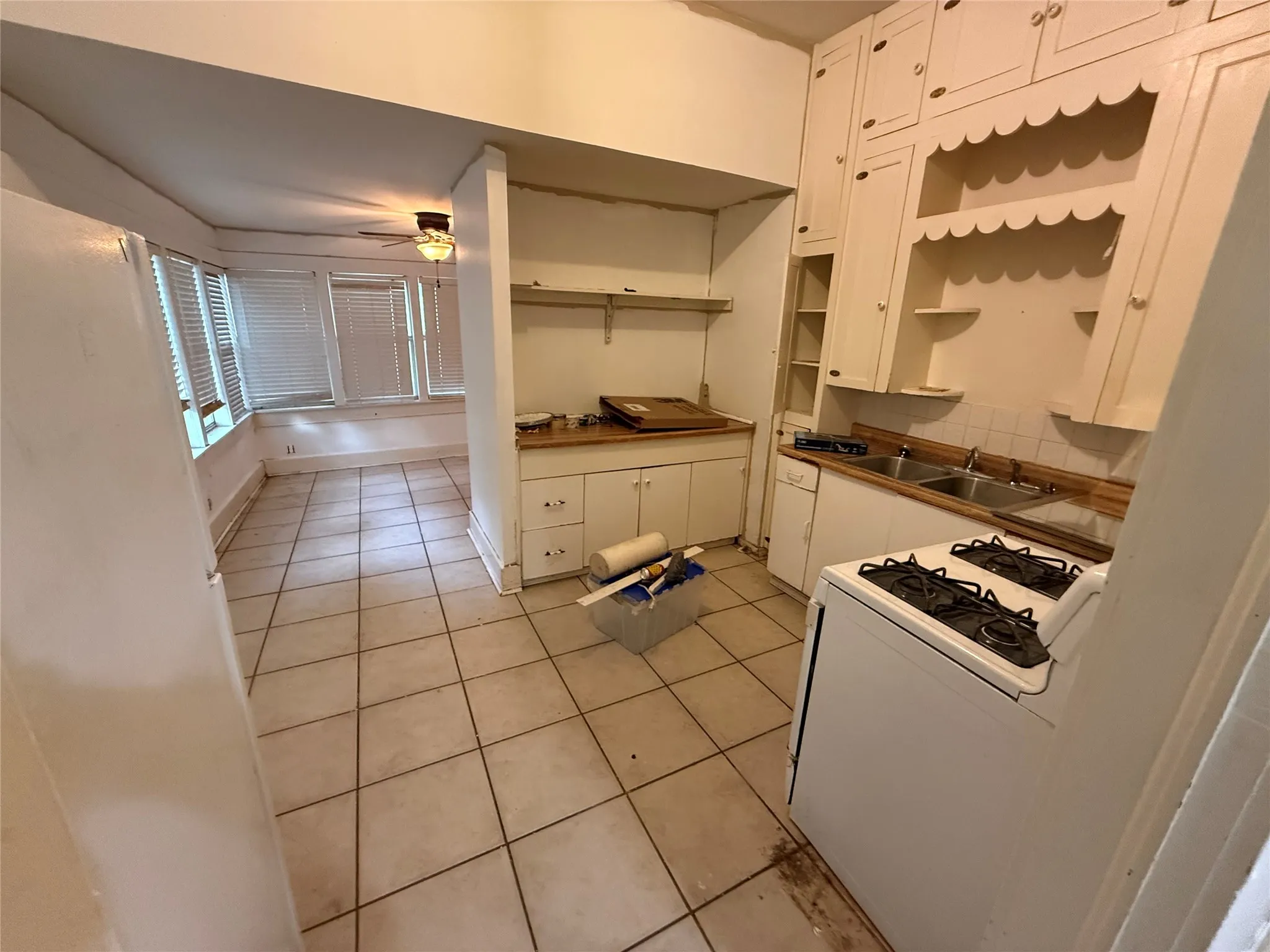 Kitchen area featuring extensive cabinetry, dual basin sink, and a gas range