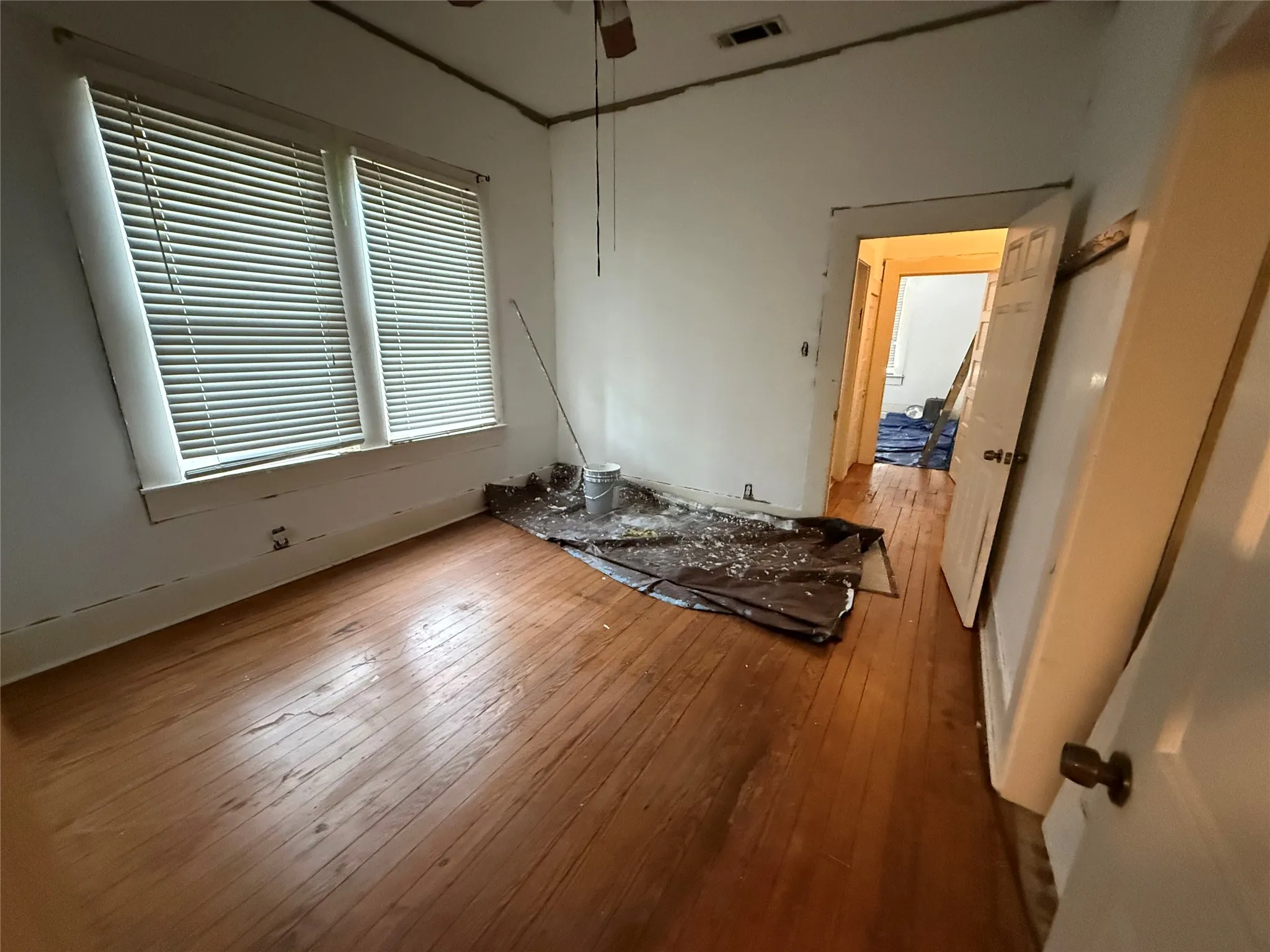 Hardwood flooring throughout, two windows with blinds, and white walls