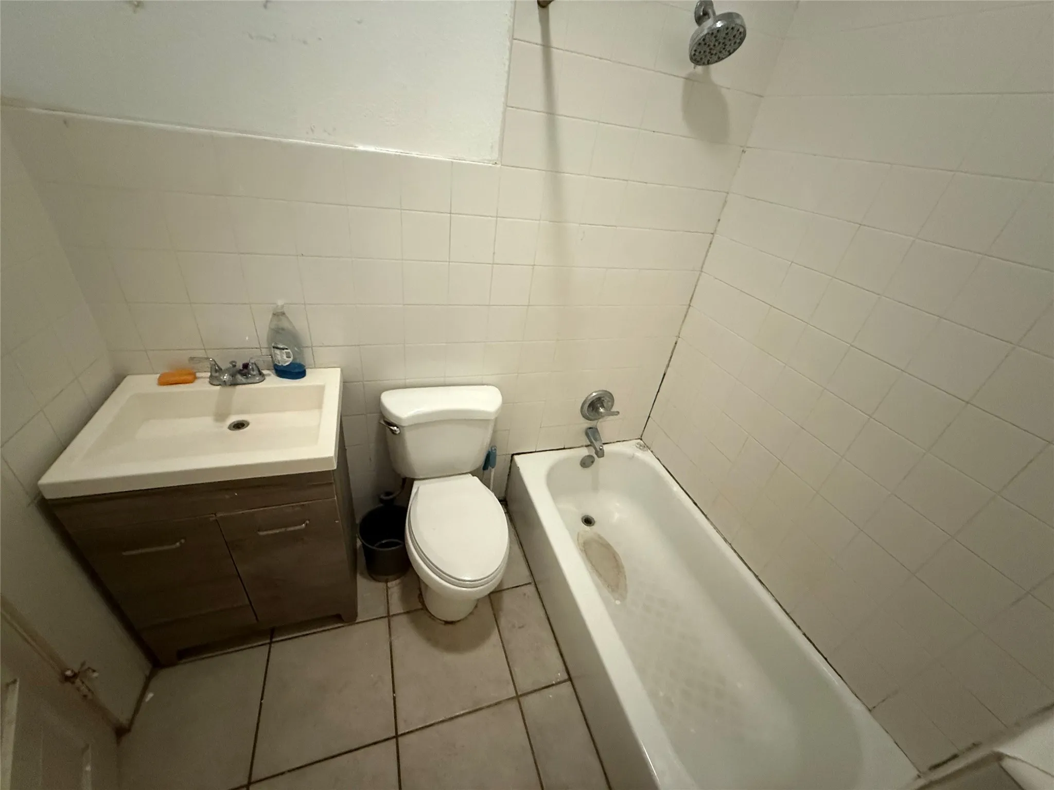 Bathroom featuring a vanity with integrated sink, toilet, and a bathtub with showerhead