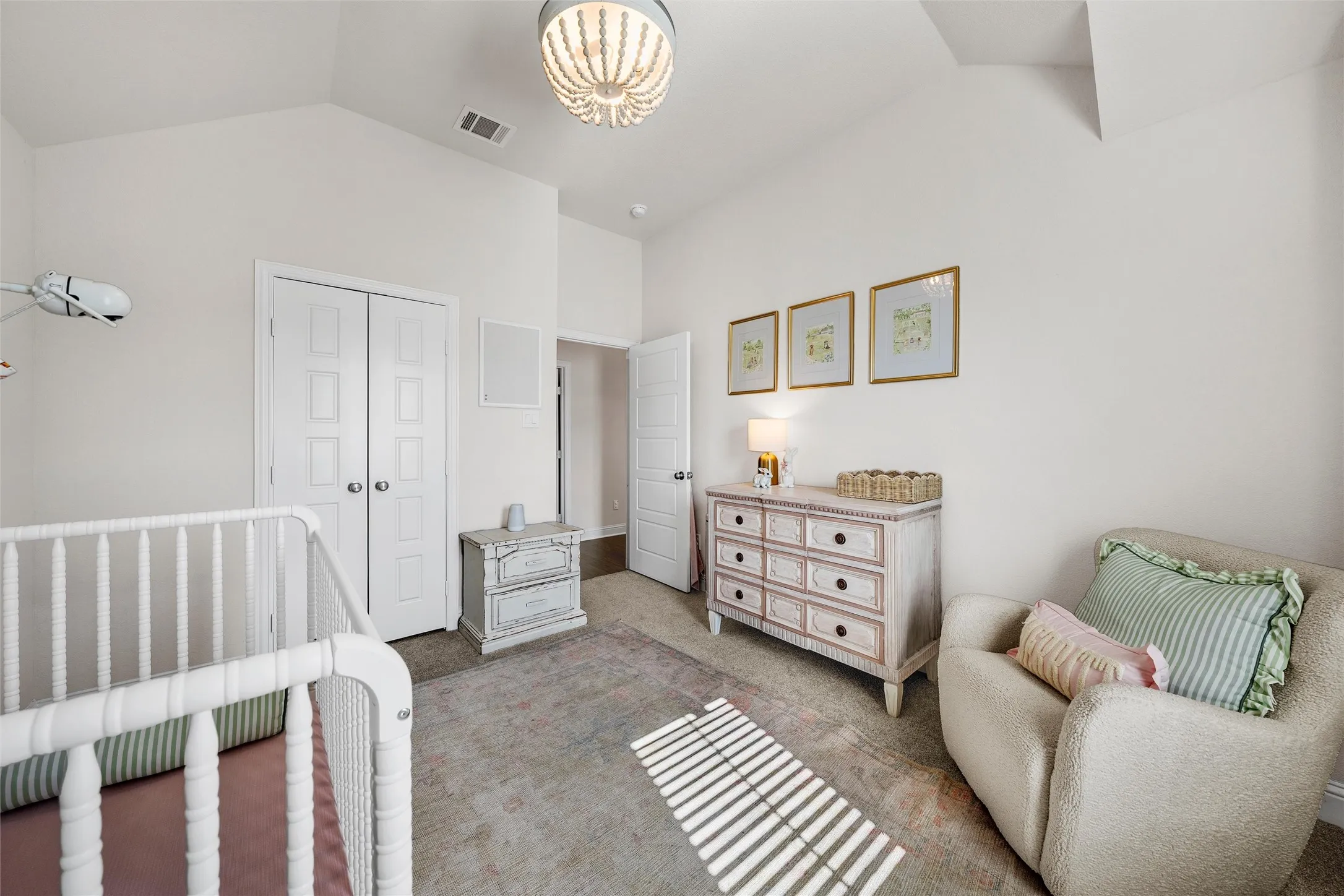 Vaulted ceiling with a decorative light fixture, carpeted flooring, and a paneled double-door closet