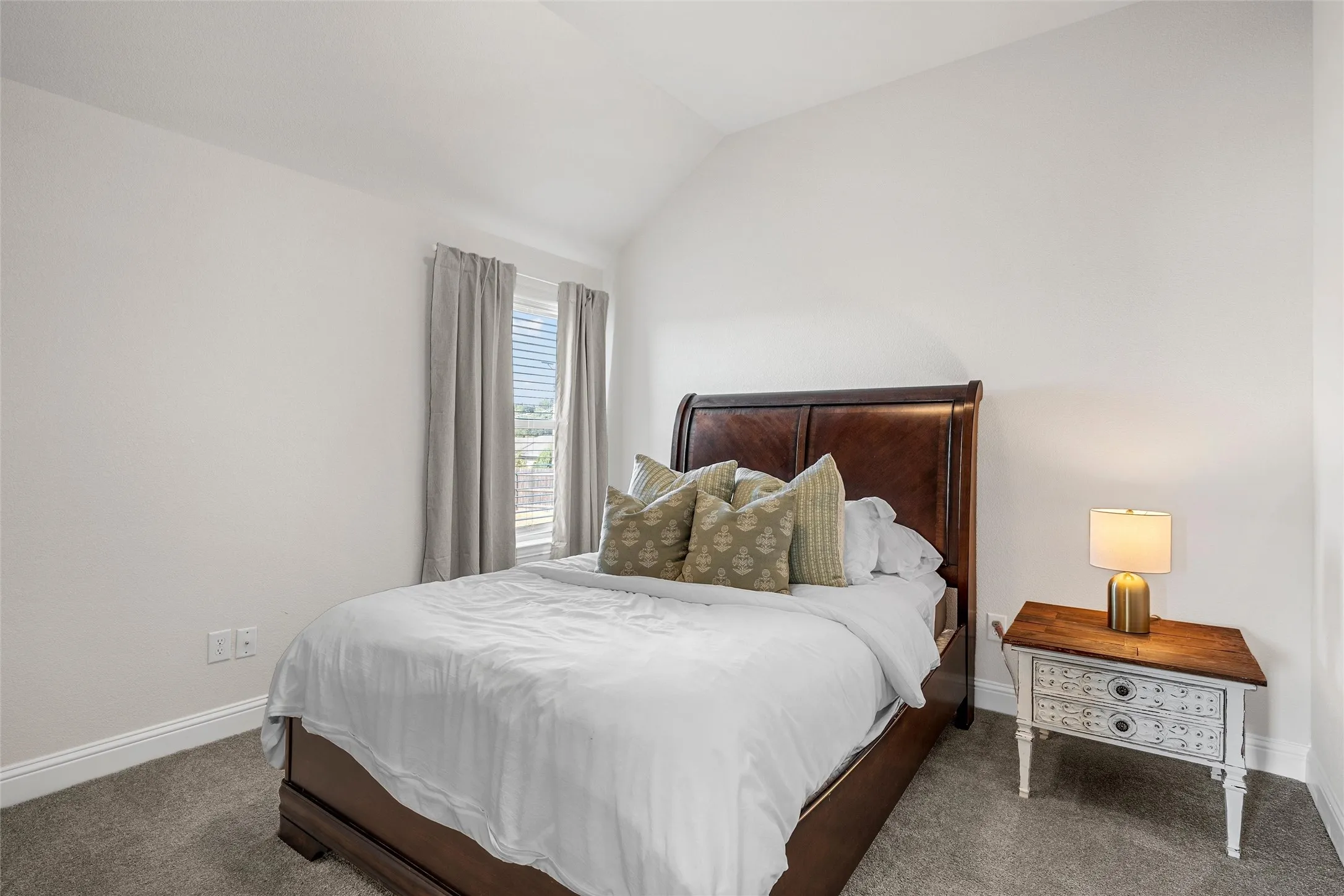 Vaulted ceiling, plush carpeting, window with blinds, and neutral wall tones