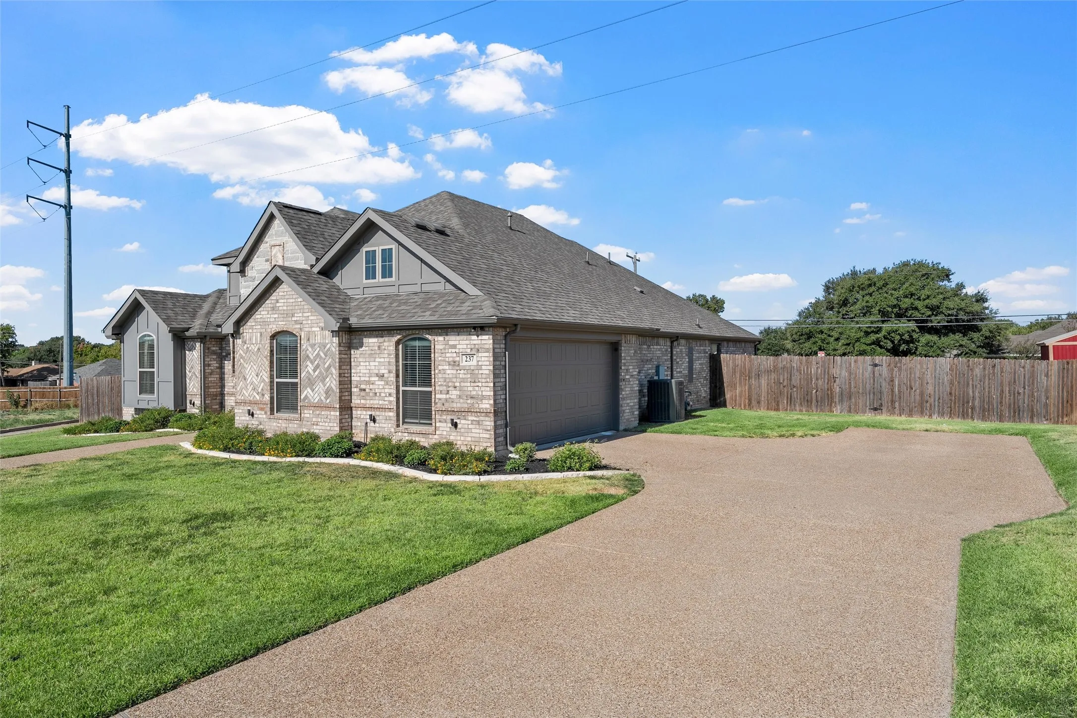 Brick and siding exterior with arched windows, attached garage, and a gravel driveway