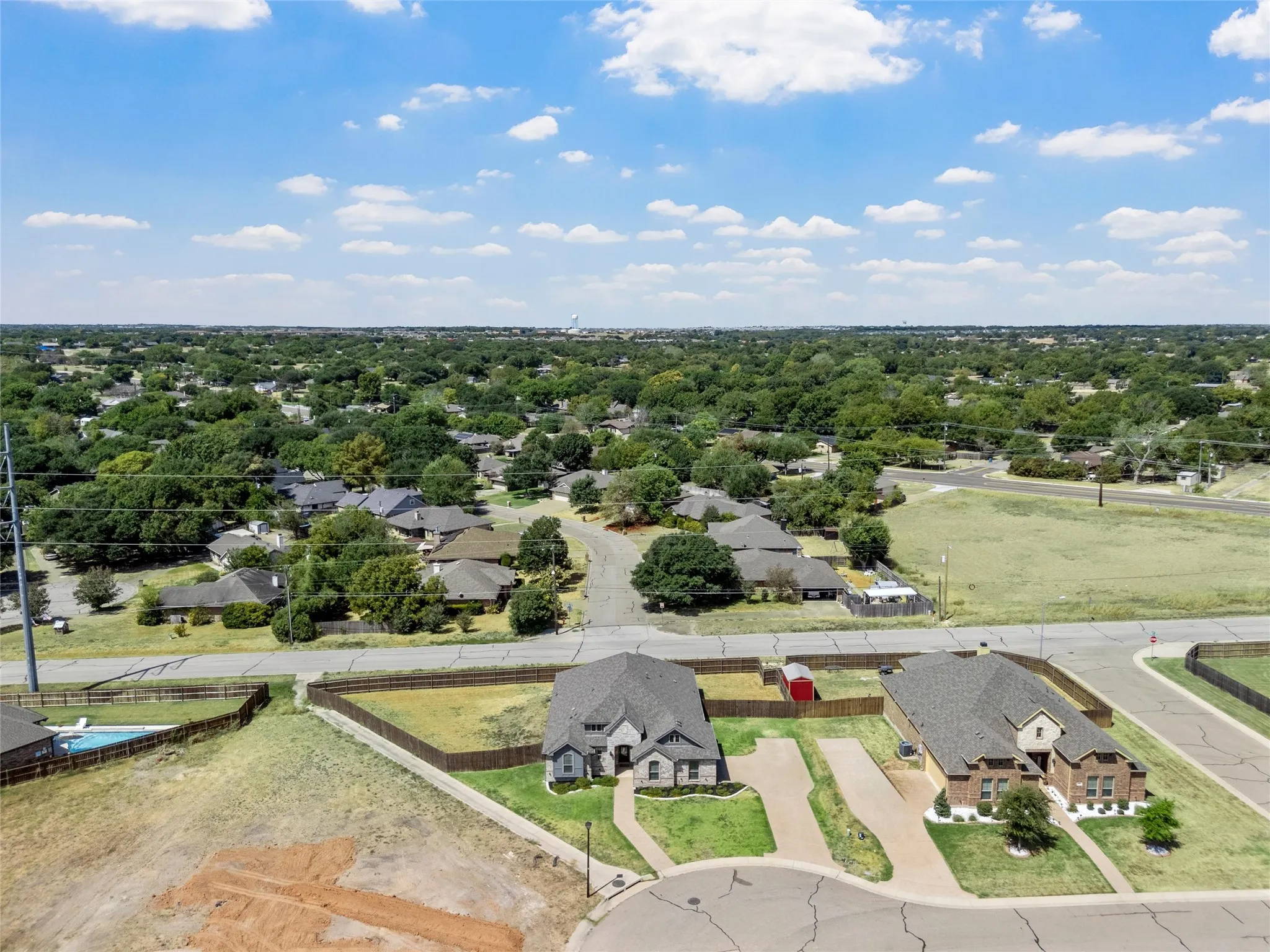 Aerial perspective showcasing the property with a dark shingle roof, attached garage, and a concrete driveway