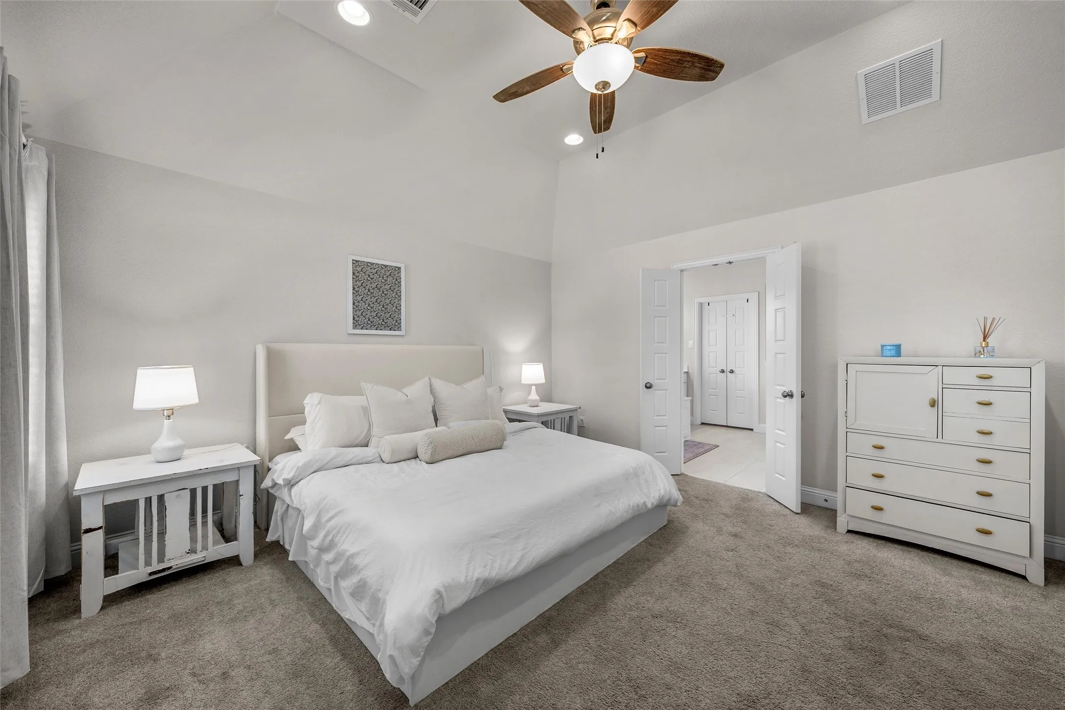Vaulted ceiling with a ceiling fan, recessed lighting, carpet flooring, and double-door entry to an additional space