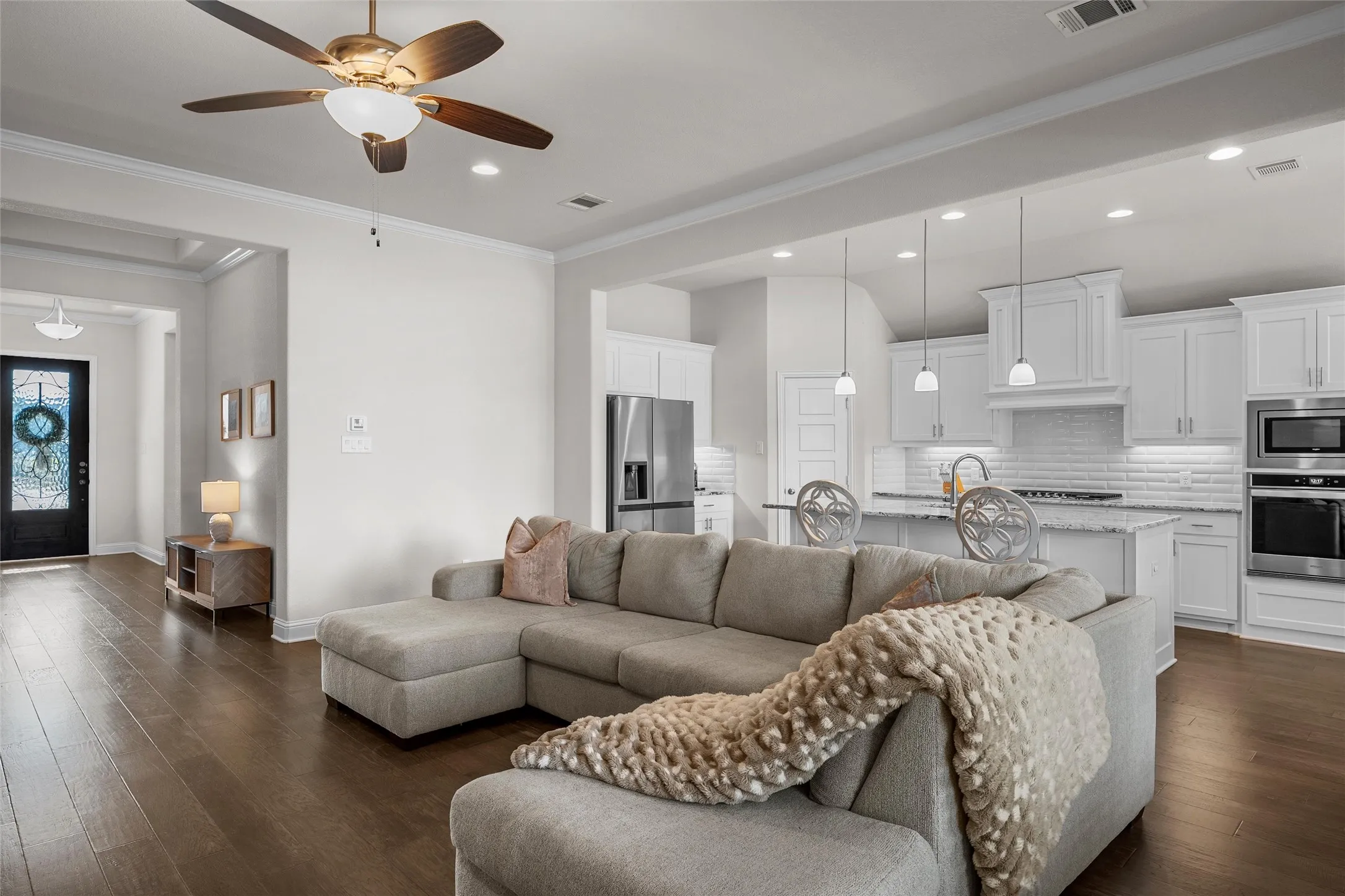 Open-concept living area featuring wood-finish flooring, recessed lighting, and a ceiling fan