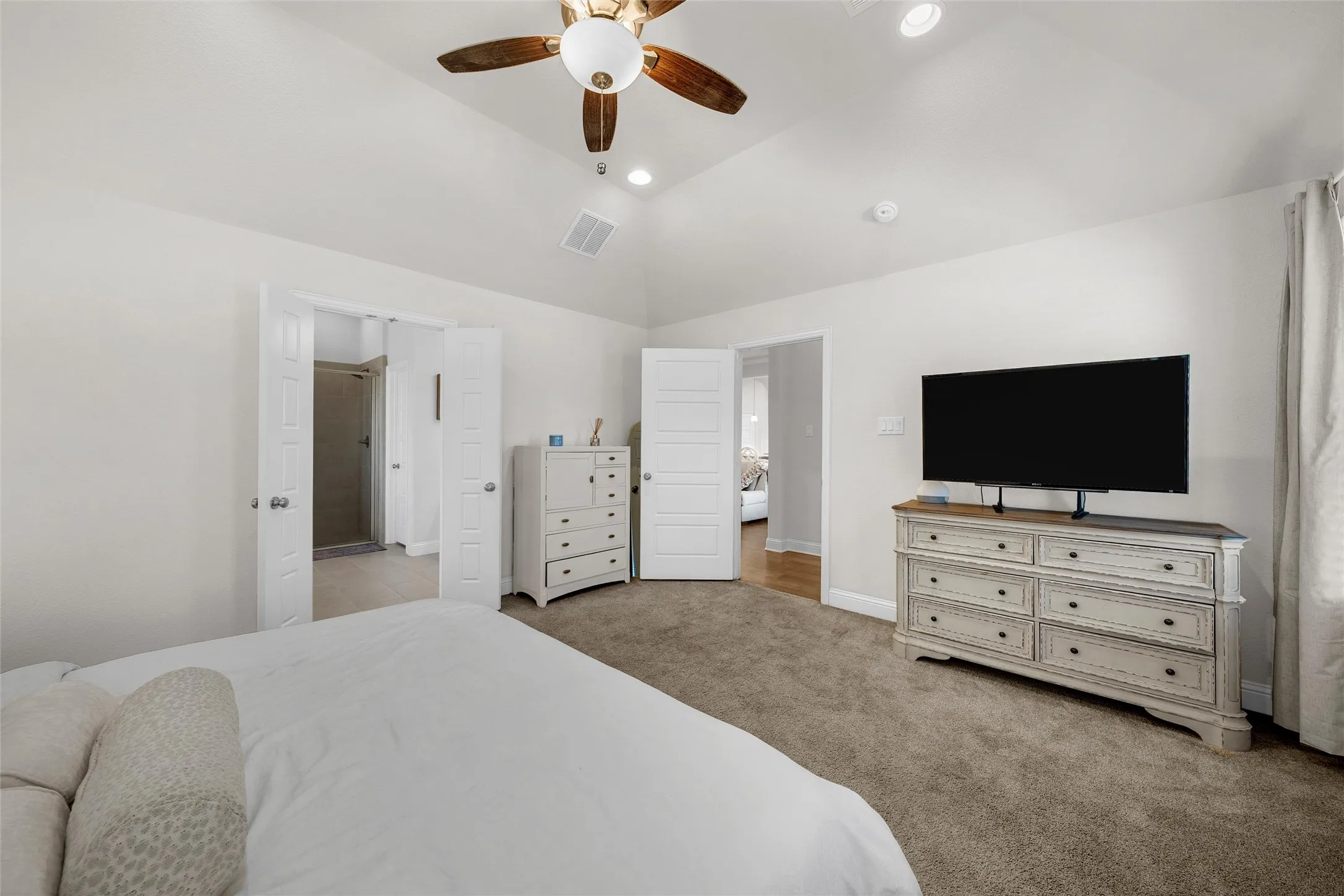 Vaulted ceiling with recessed lighting and a ceiling fan, carpeted flooring, and white interior doors