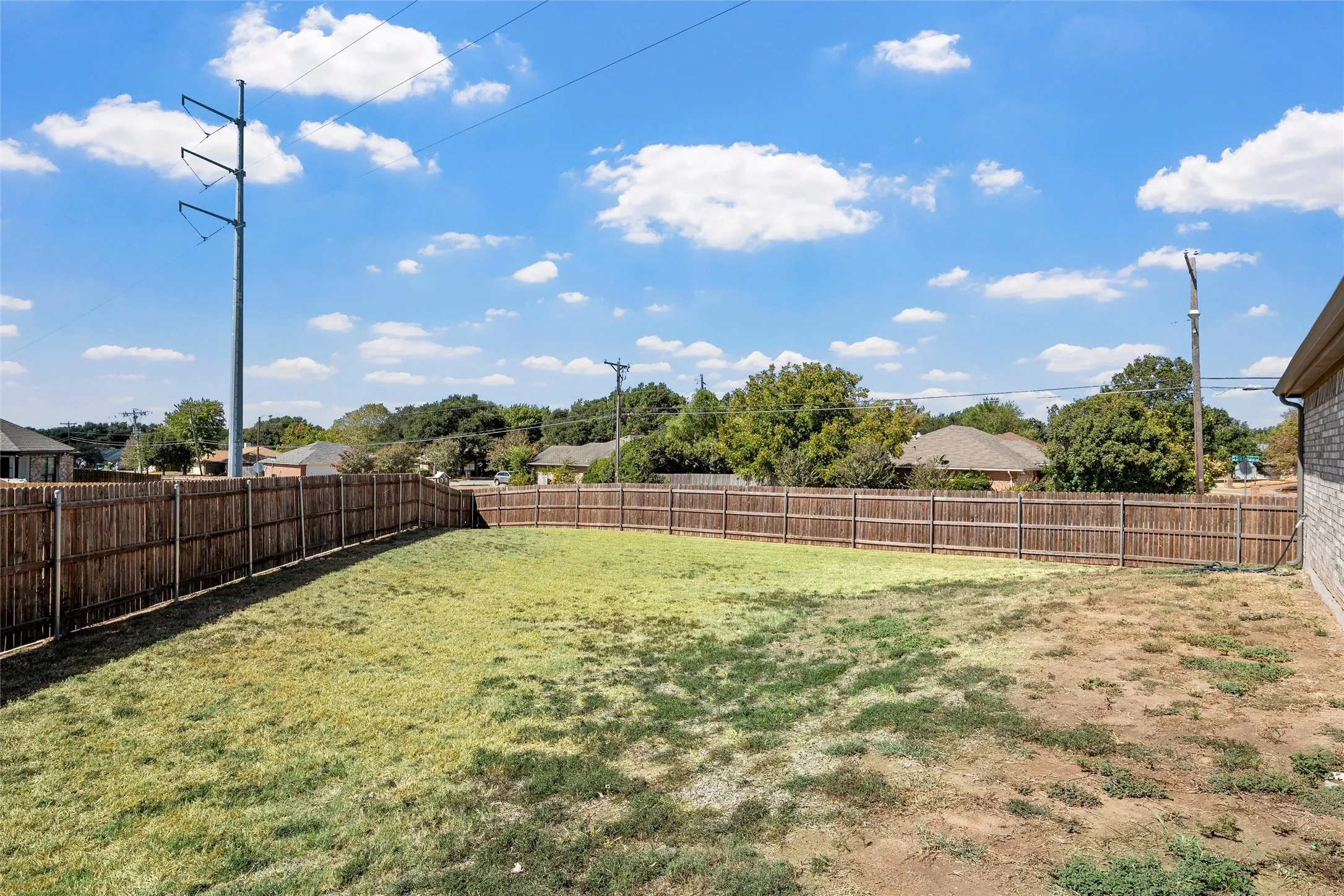 Expansive backyard featuring a wood privacy fence and a brick-finish exterior
