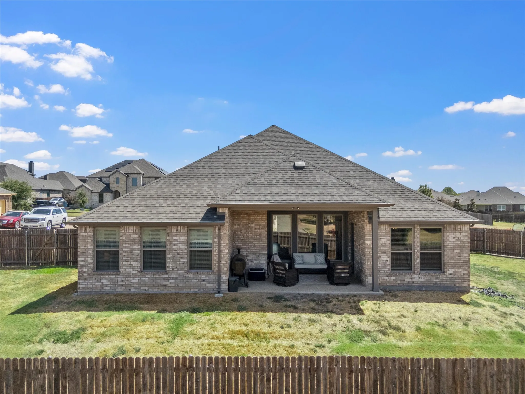 Brick exterior featuring a covered patio and a wood fence
