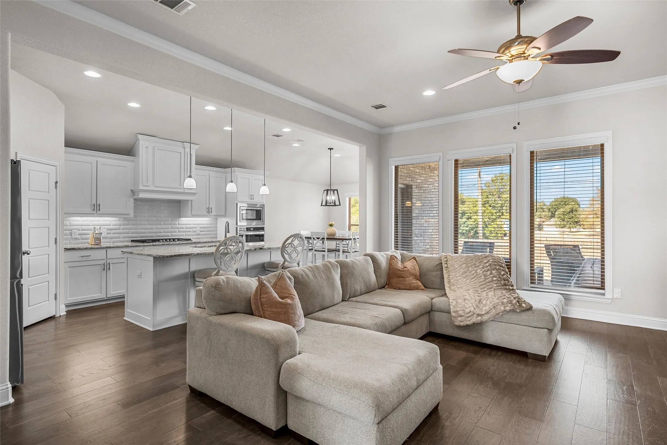 Open-concept living area with dark wood-finish flooring, recessed lighting, and a ceiling fan