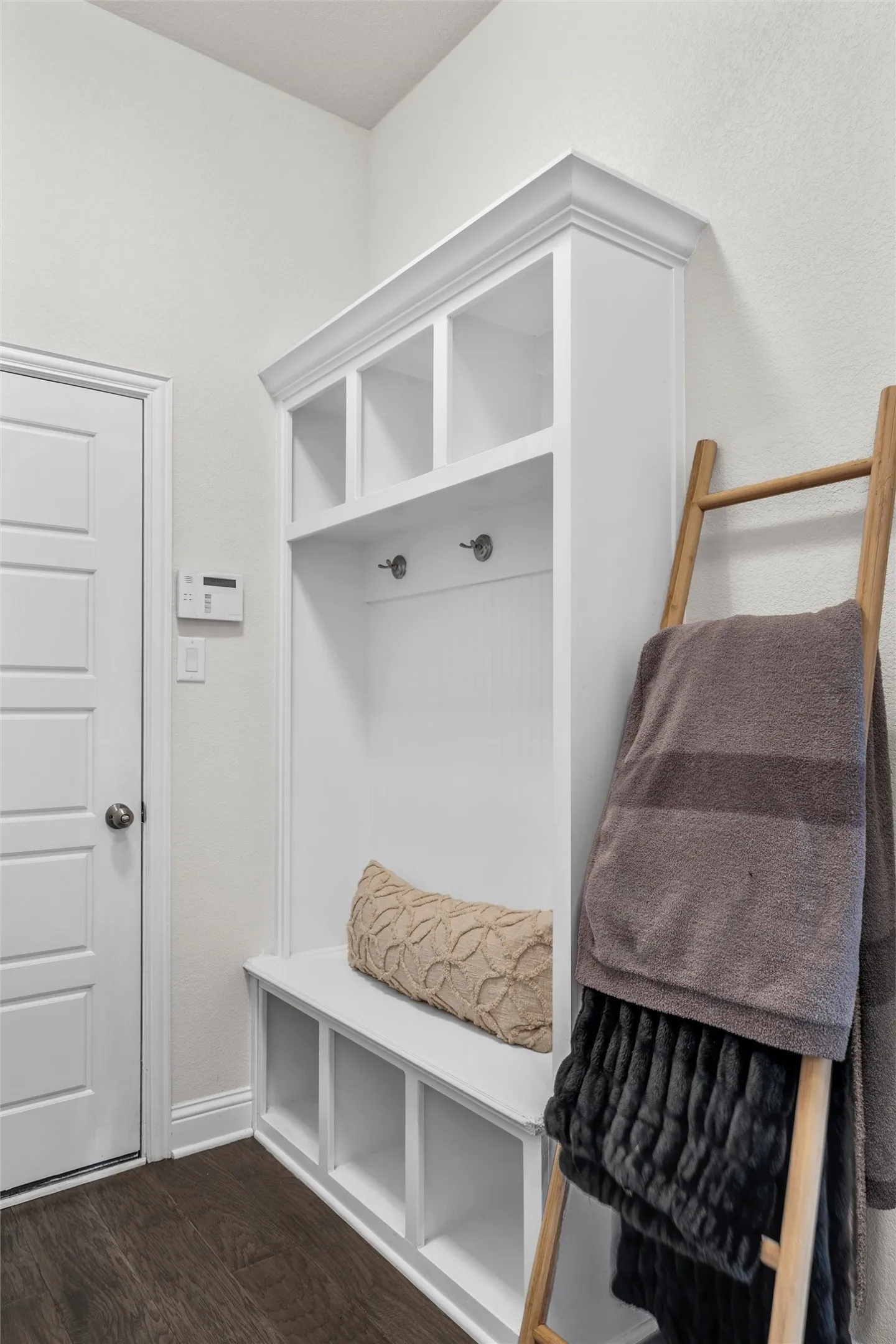 Built-in mudroom bench with cubby storage, upper shelving, and coat hooks
