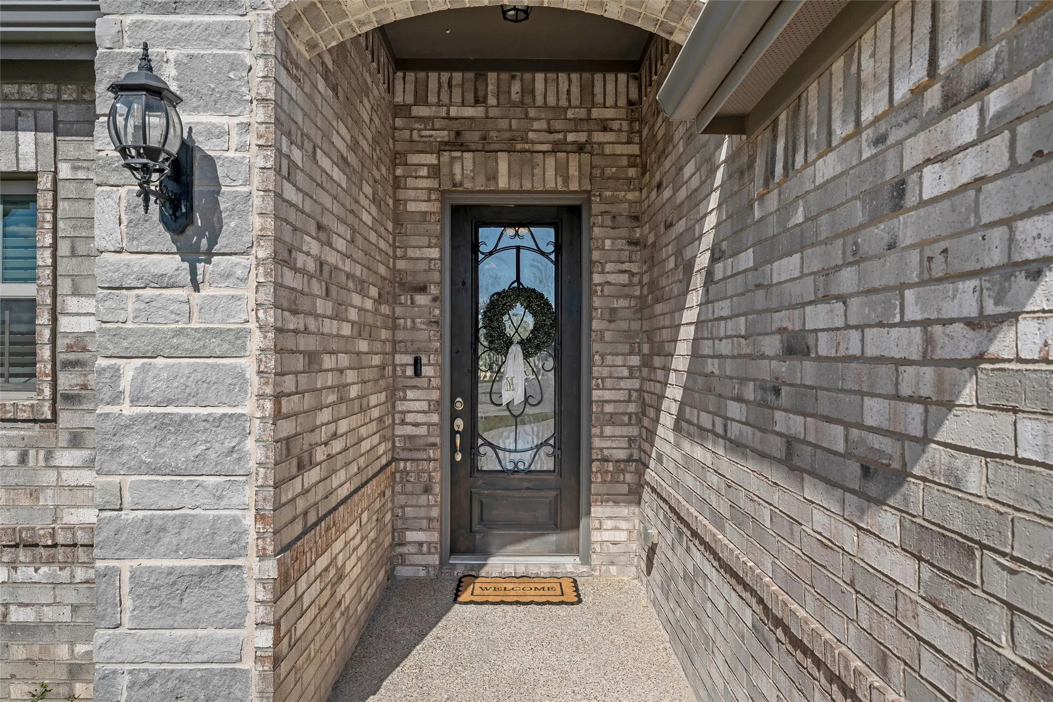 Arched entryway with a dark wood-finish door featuring decorative glass