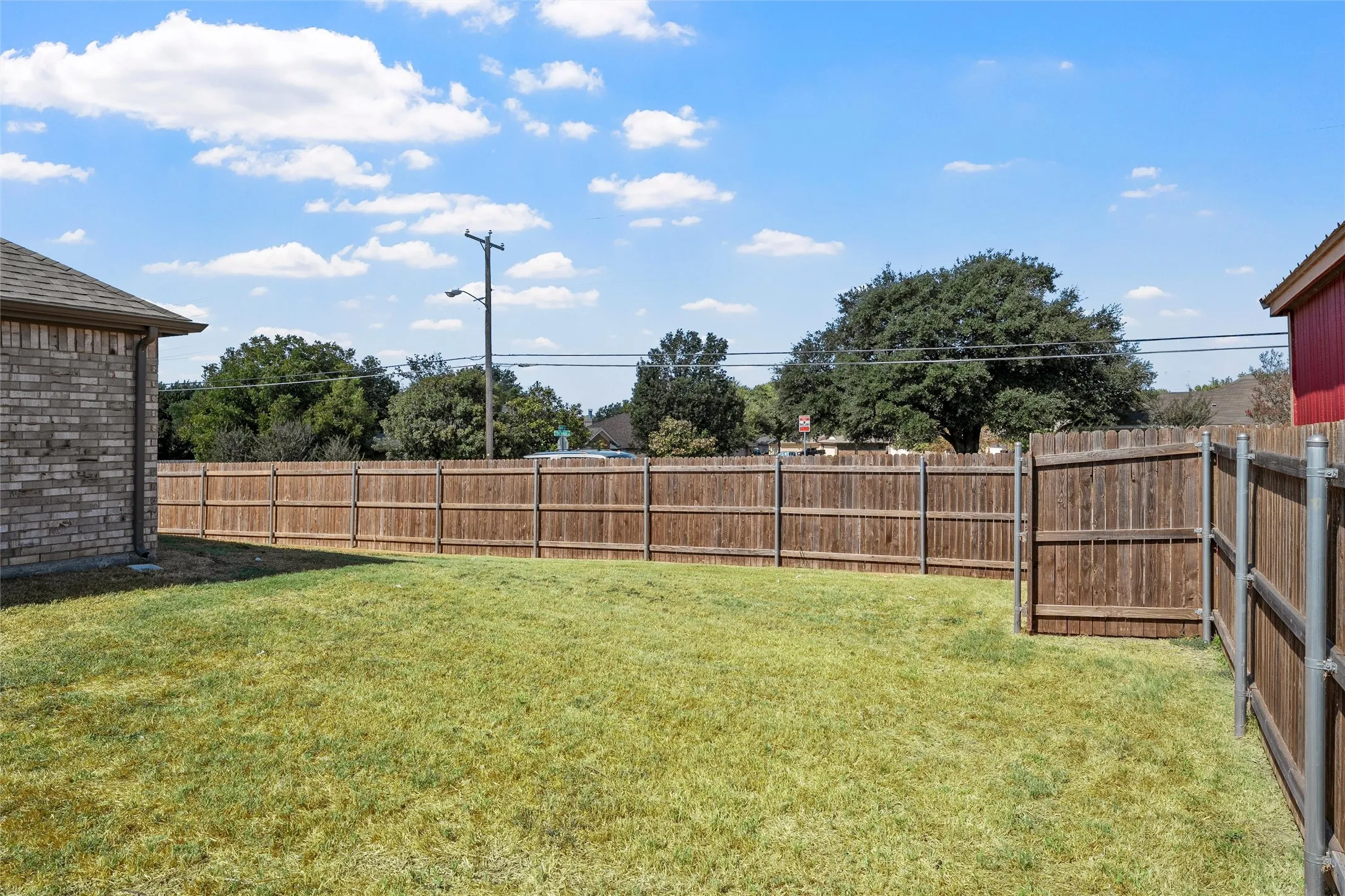 Expansive grassy backyard with a wood privacy fence