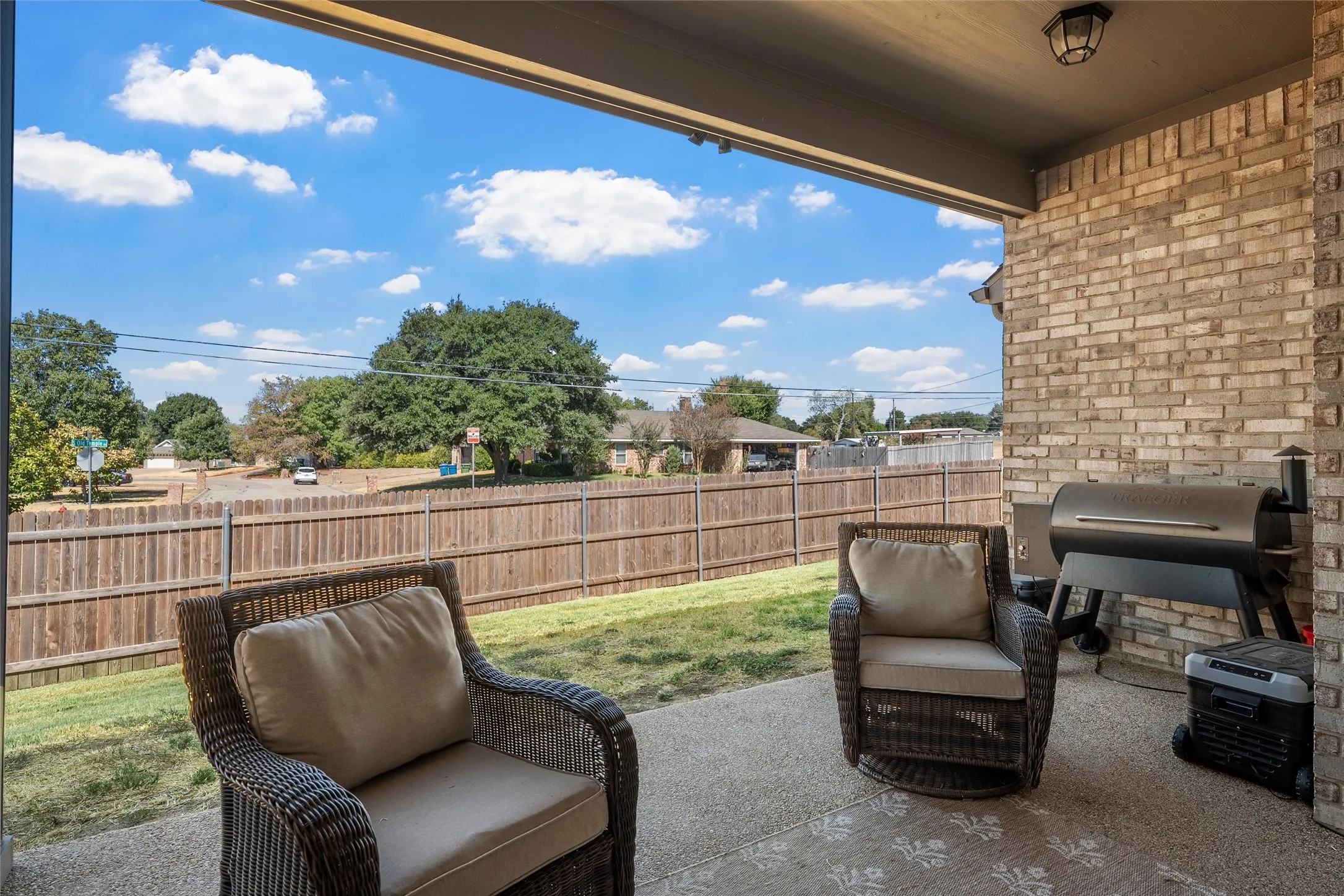 Covered patio with a brick exterior wall, concrete flooring, and an overhead light fixture