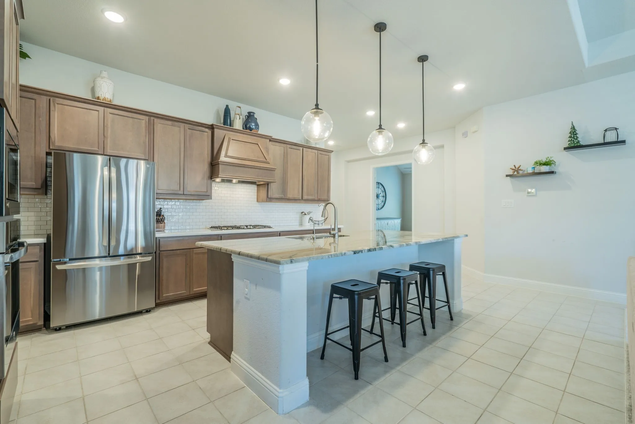 Kitchen featuring stainless steel appliances, wood cabinetry, subway tile backsplash, a kitchen island with seating, and recessed lighting