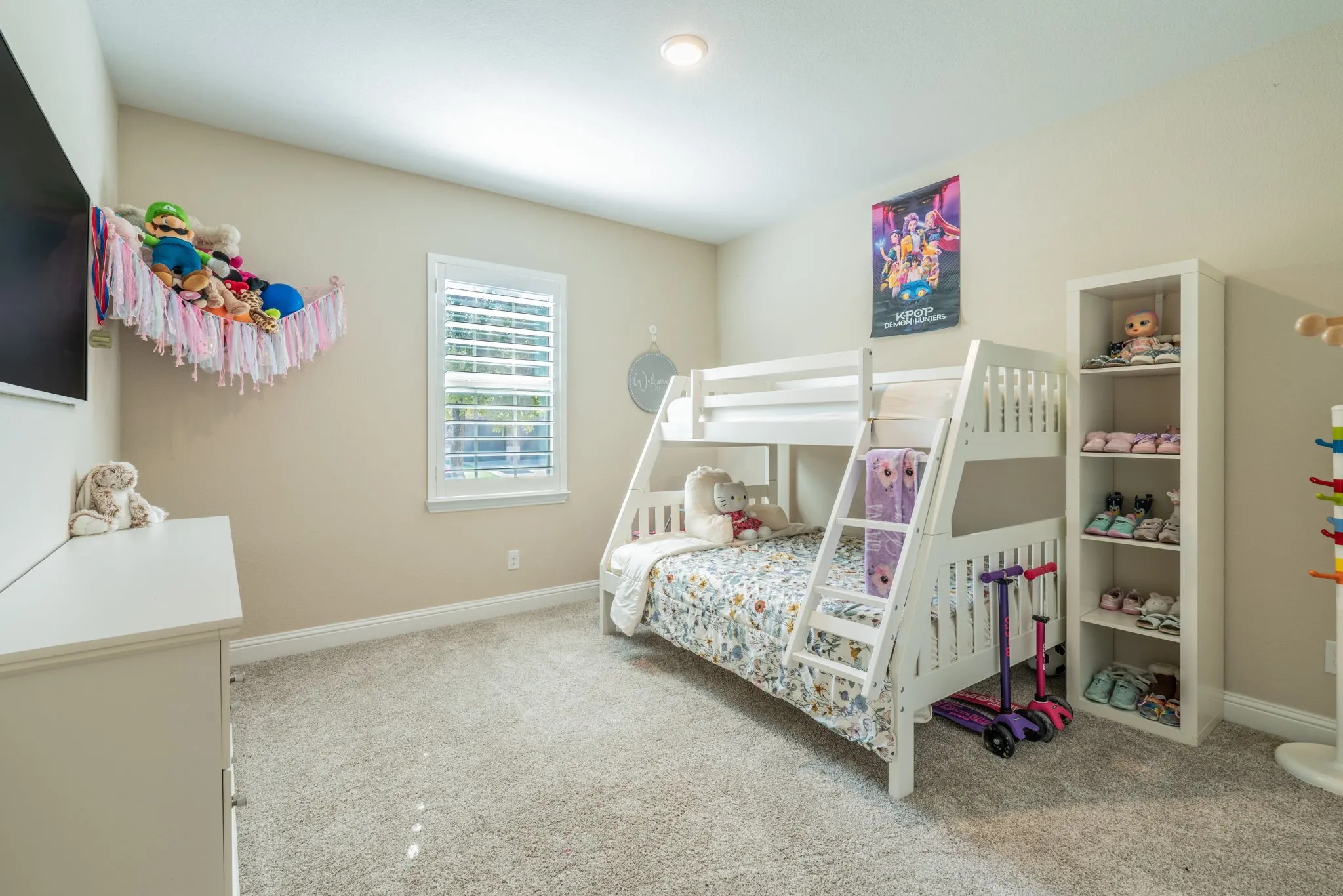 Plush carpet flooring, recessed ceiling lighting, and a window with plantation shutters