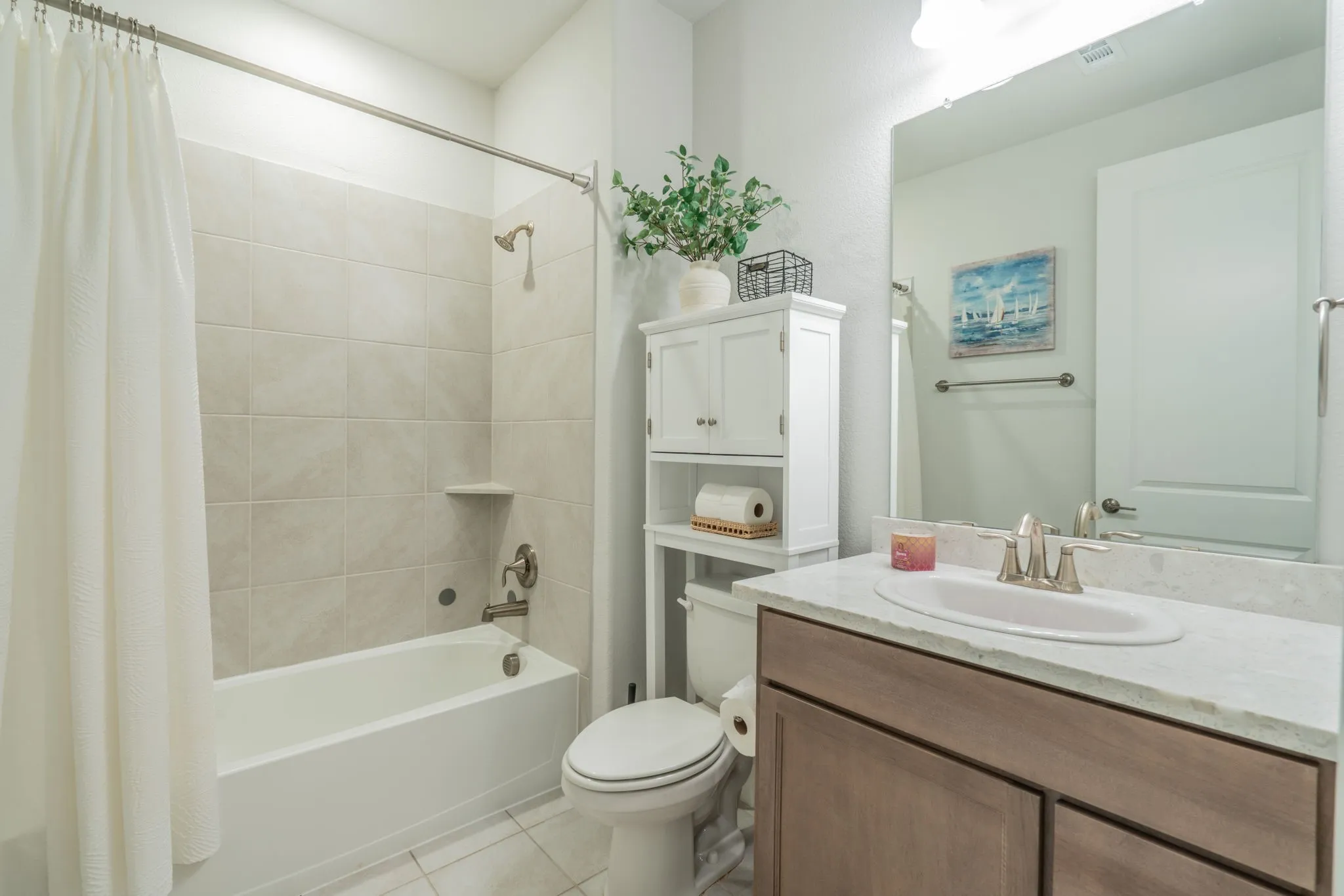 Bathtub with a tiled surround, single vanity with a solid surface countertop, and a built-in cabinet