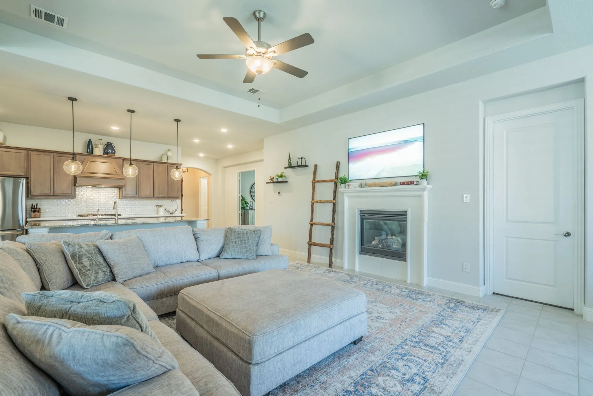 Recessed lighting, ceiling fan, fireplace with mantel, tray ceiling, and tile flooring