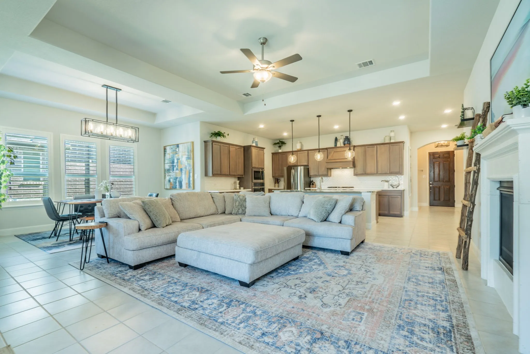 Open-concept living area featuring a tray ceiling, recessed lighting, and tile flooring