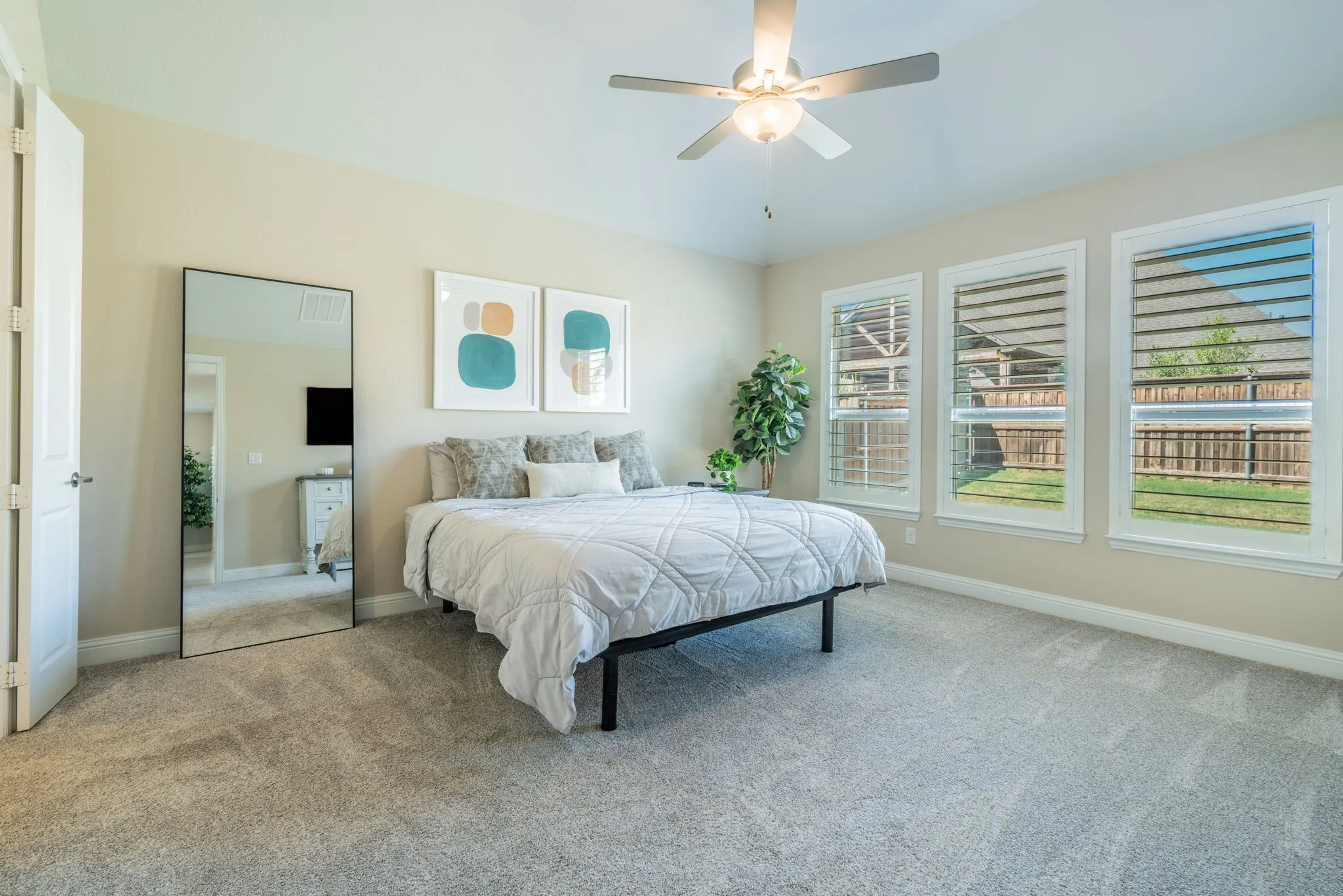 Carpeted room with a ceiling fan, three windows with blinds, and neutral wall tones