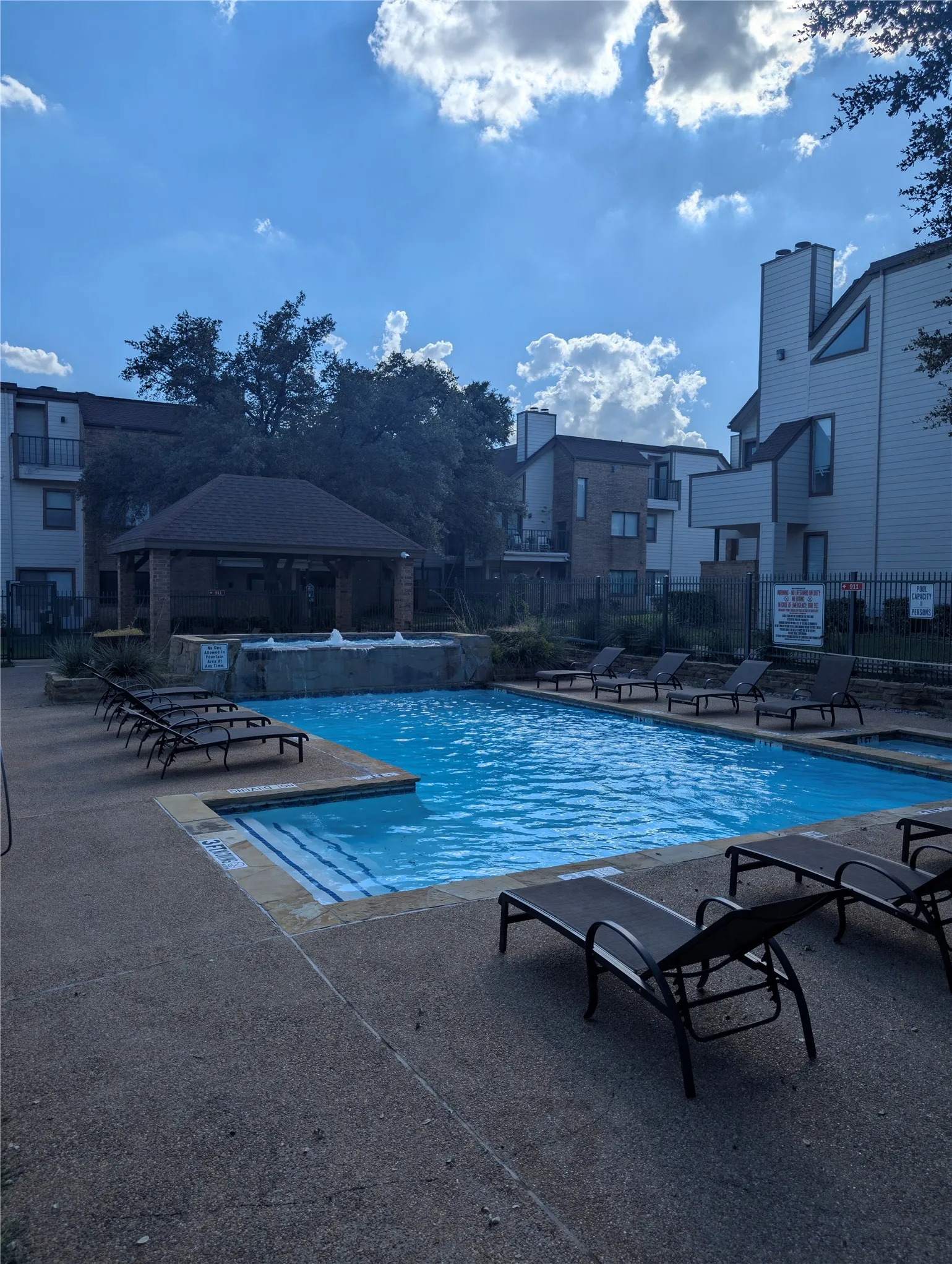 Resort-style pool with integrated spa and water feature, surrounded by a concrete deck