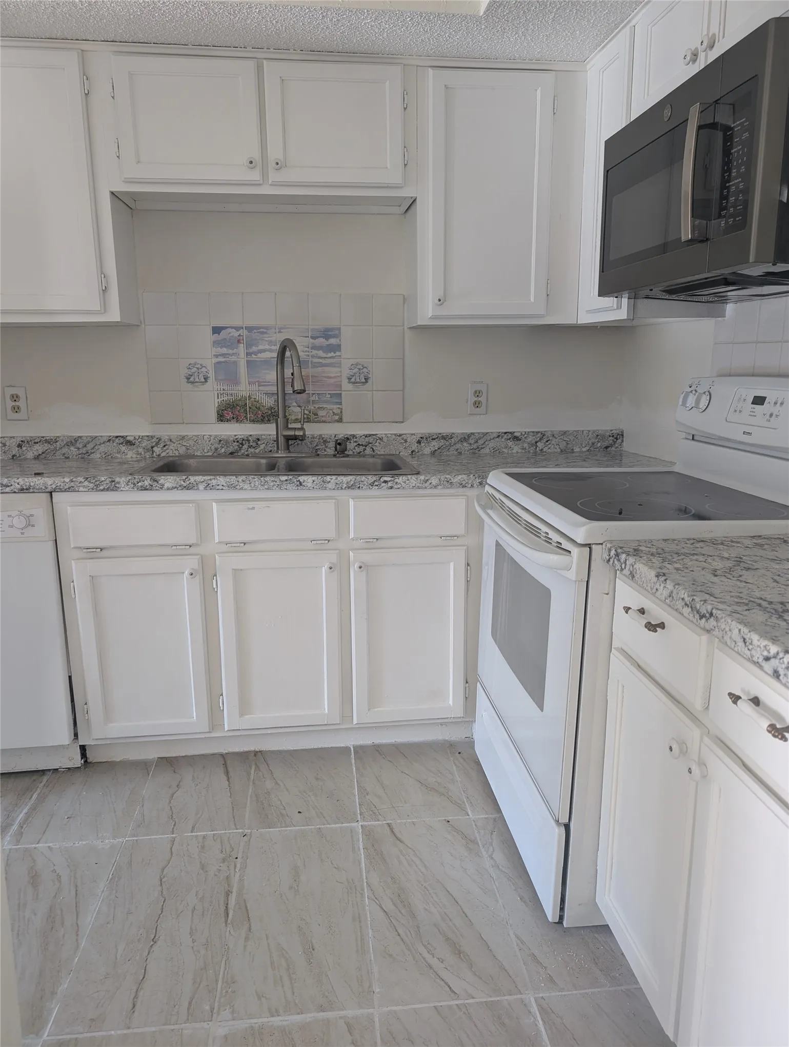 White cabinetry, stone-look countertops, stainless steel sink with gooseneck faucet, tile backsplash, and large format floor tiling
