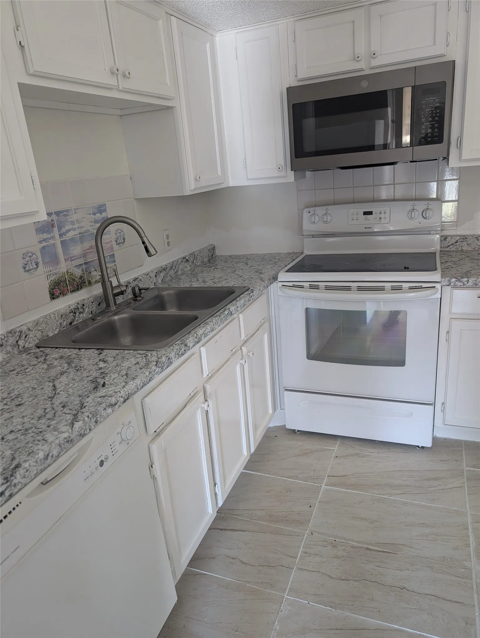 White cabinetry, light-toned countertops, stainless steel sink, over-the-range microwave, and a white electric range