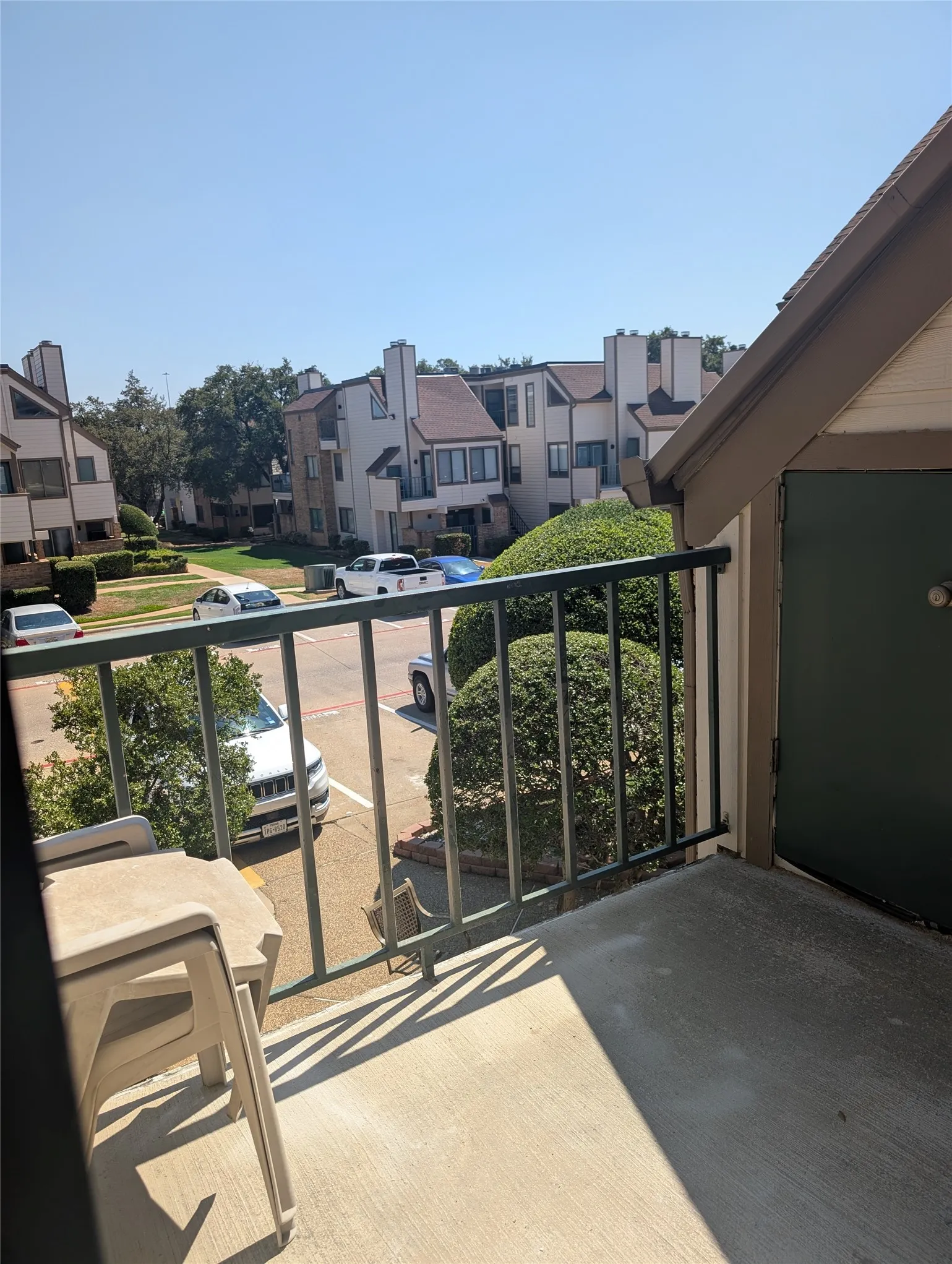 Concrete balcony with a dark metal railing  and green storage unit