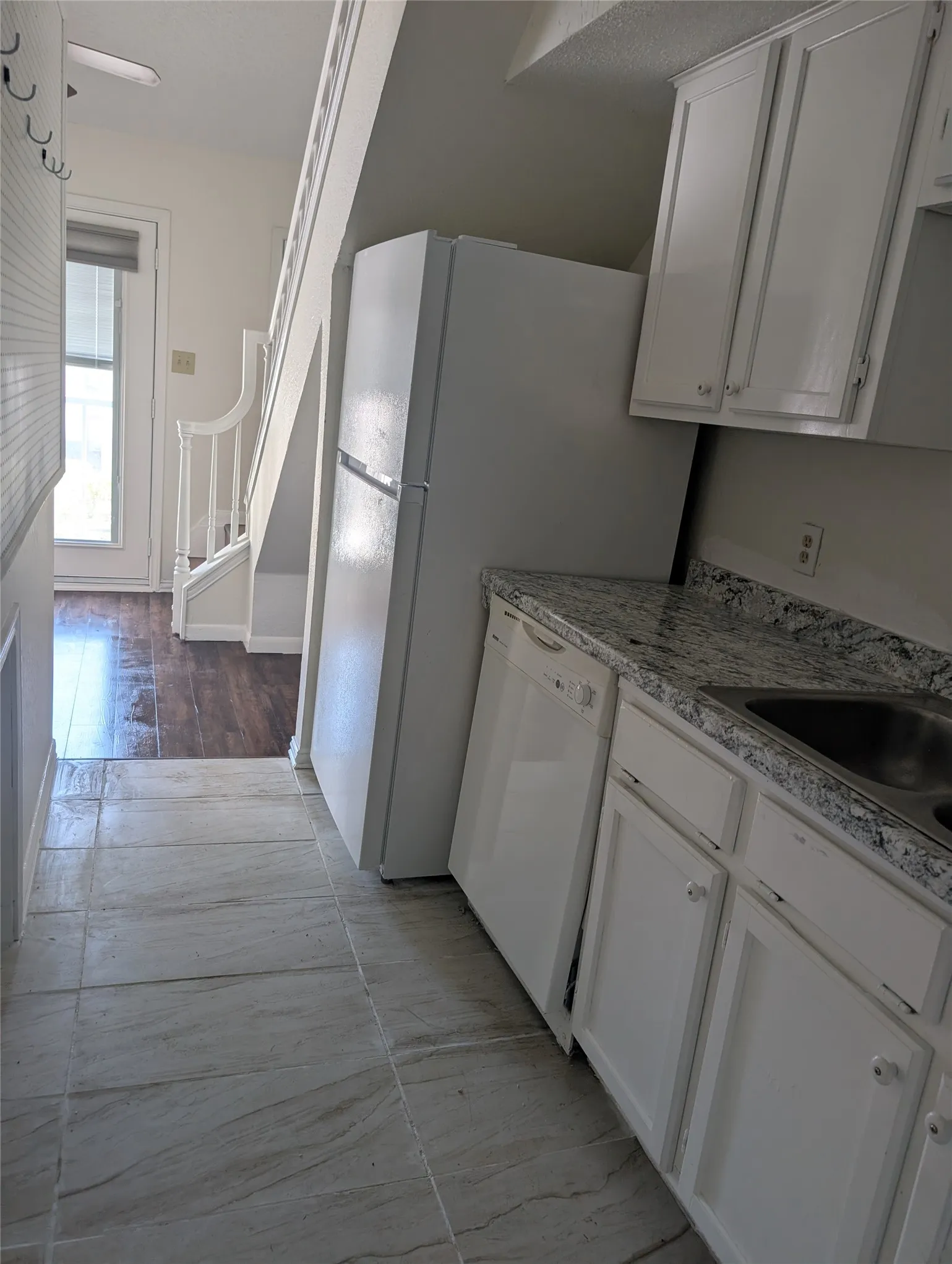 Kitchen featuring white cabinetry, a built-in dishwasher, and a stainless steel sink