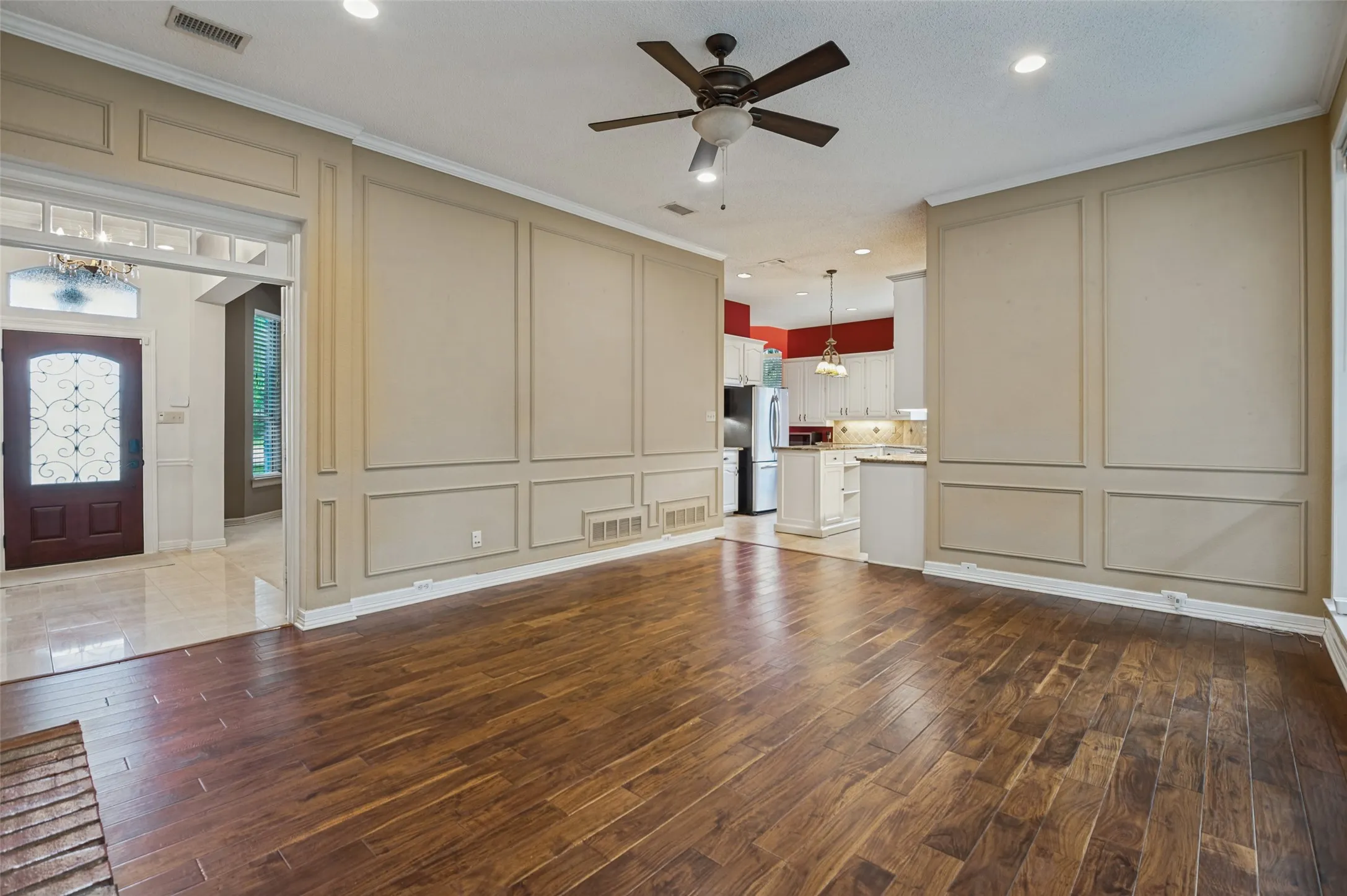Wood-finish flooring, decorative wall paneling, ceiling fan, recessed lighting, and crown molding
