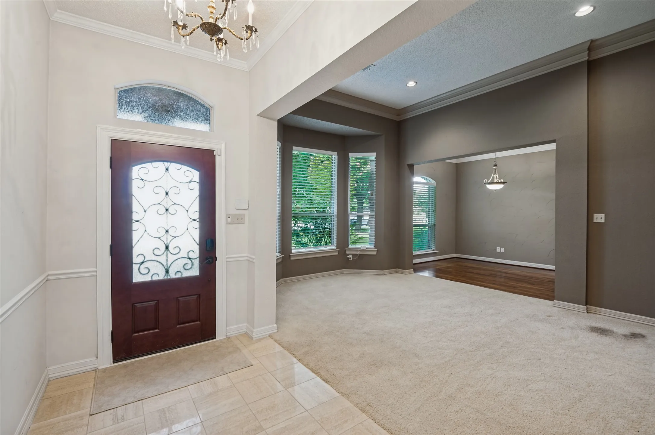 Entryway featuring a decorative inlaid glass door with transom window, tile flooring, and an ornate chandelier