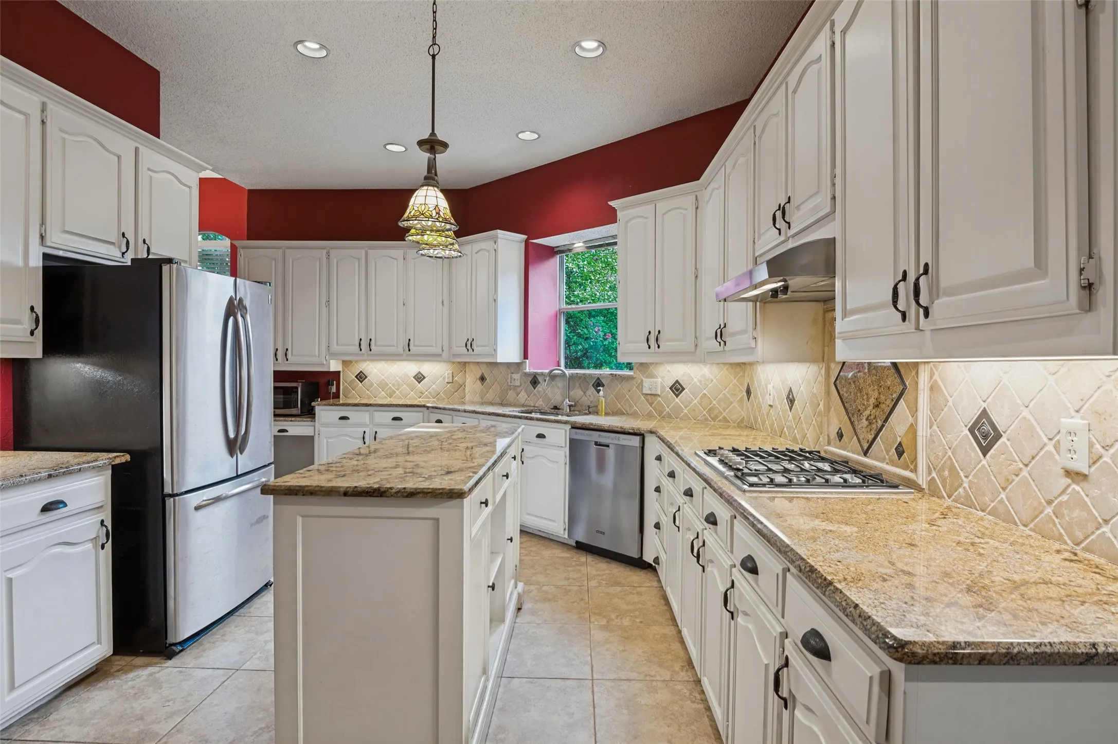 Spacious kitchen with white cabinetry, granite countertops, a tiled backsplash, kitchen island, and recessed lighting