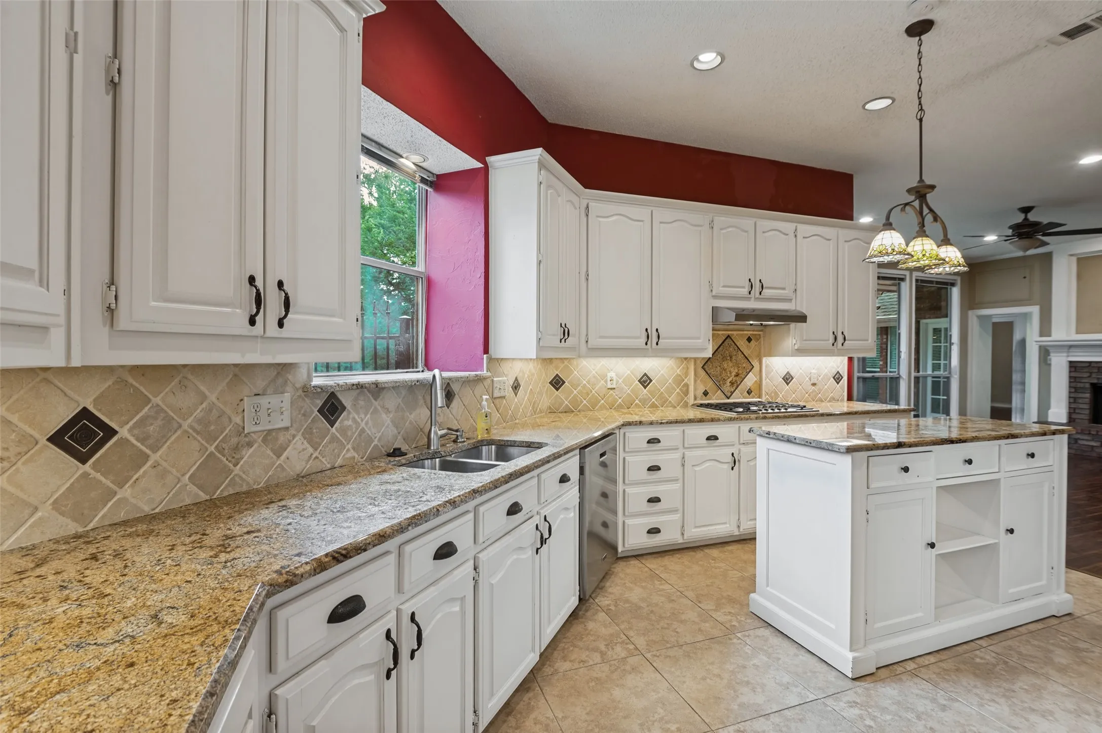 White cabinetry with dark hardware, stone countertops, tiled backsplash, center island, and recessed lighting