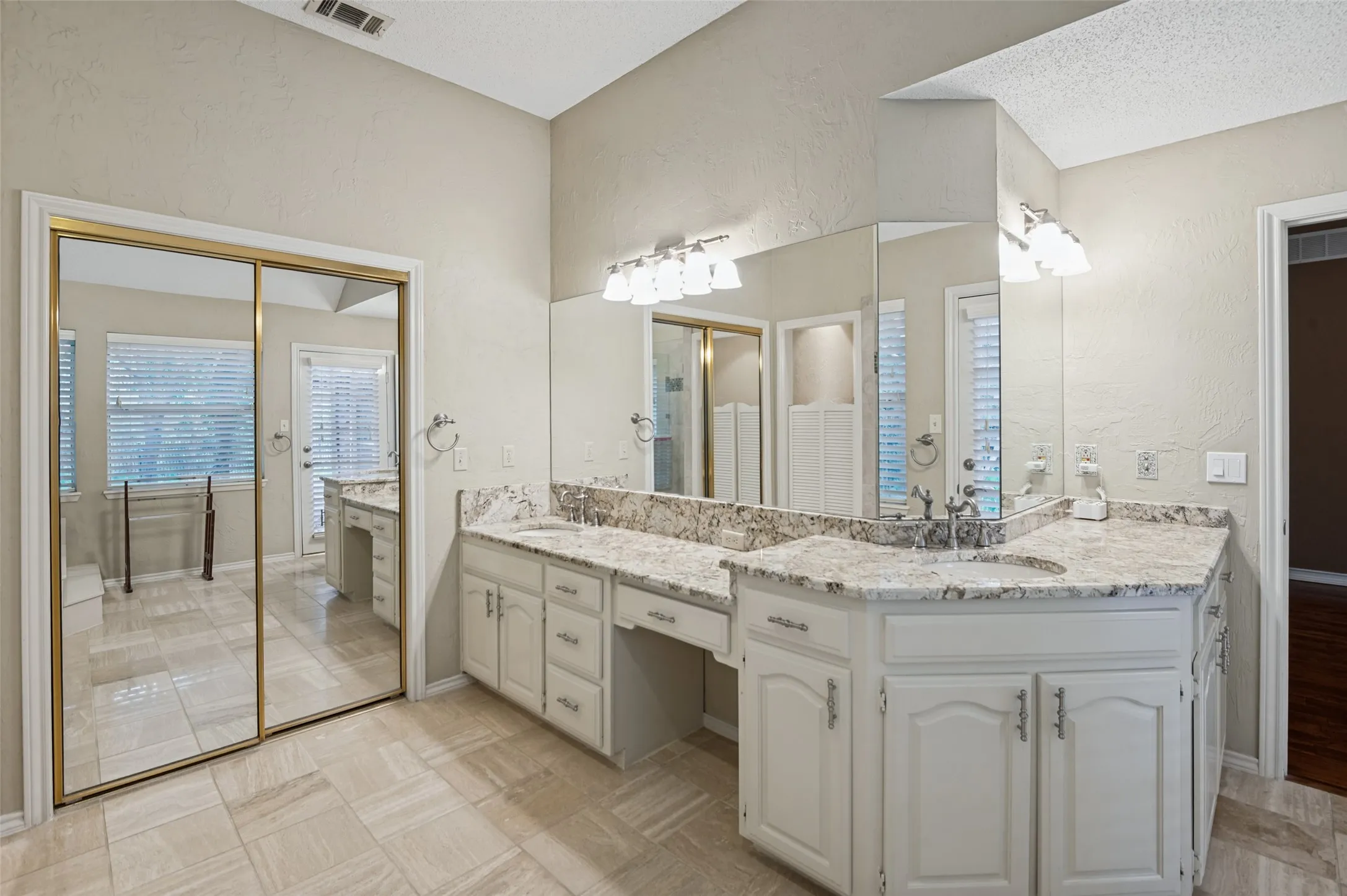 Dual vanity with undermount sinks and light-toned countertops, white cabinetry, and wall-mounted light fixtures