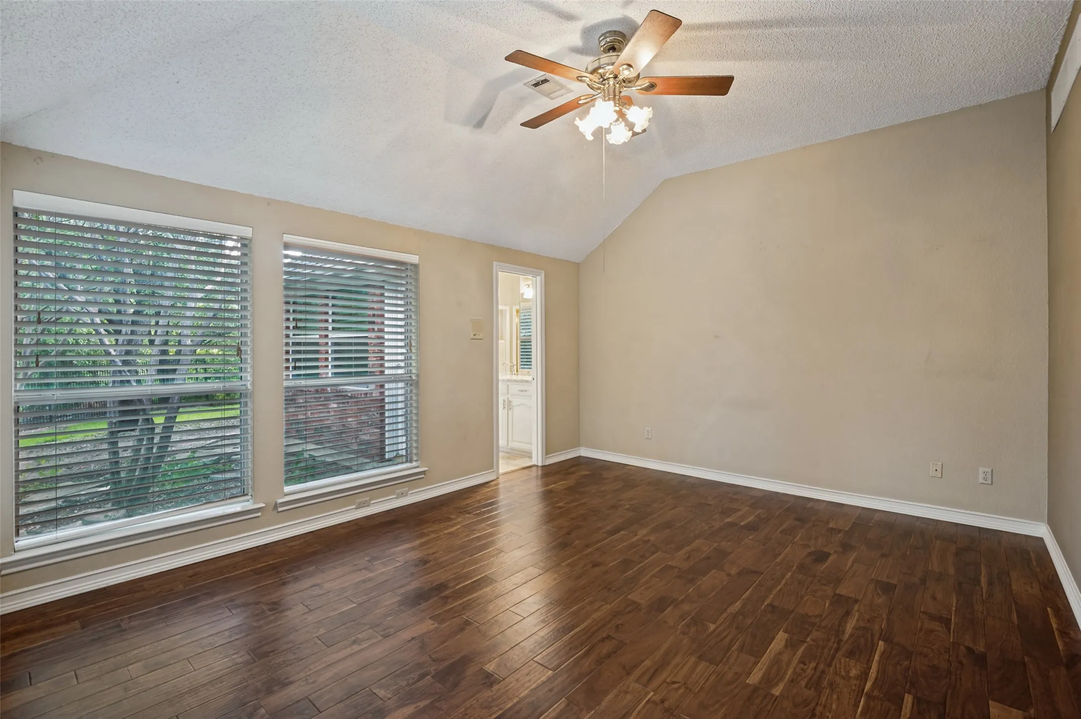 Vaulted ceiling, wood-finish flooring, dual windows with blinds, and ceiling fan with integrated lighting