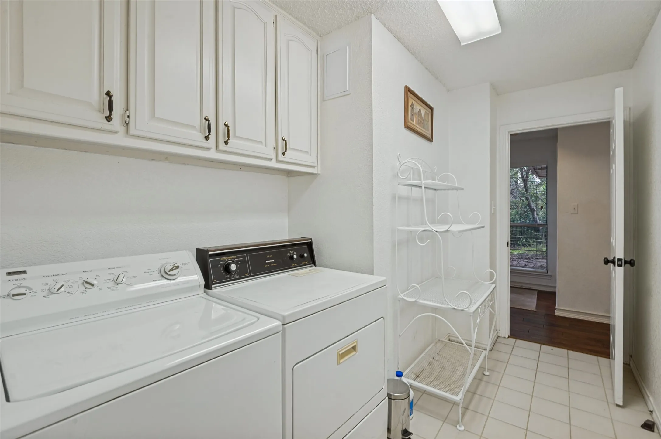 White cabinetry with dark hardware, tile flooring, and overhead lighting