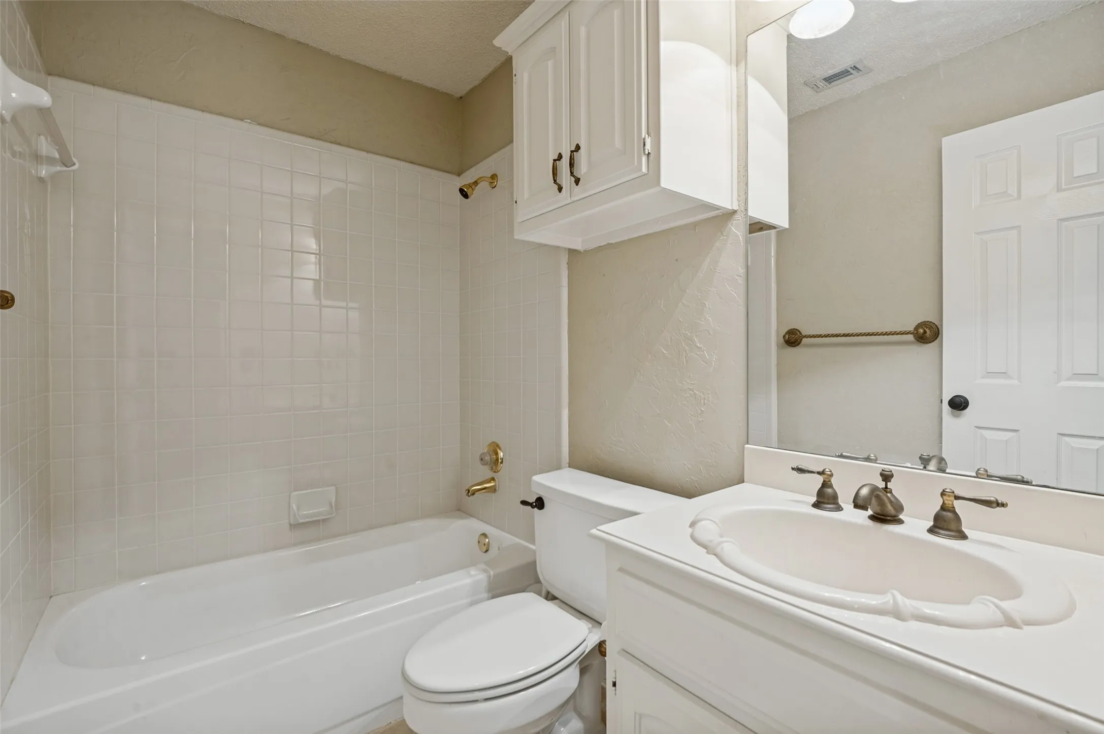 White tile surround bathtub with brass fixtures