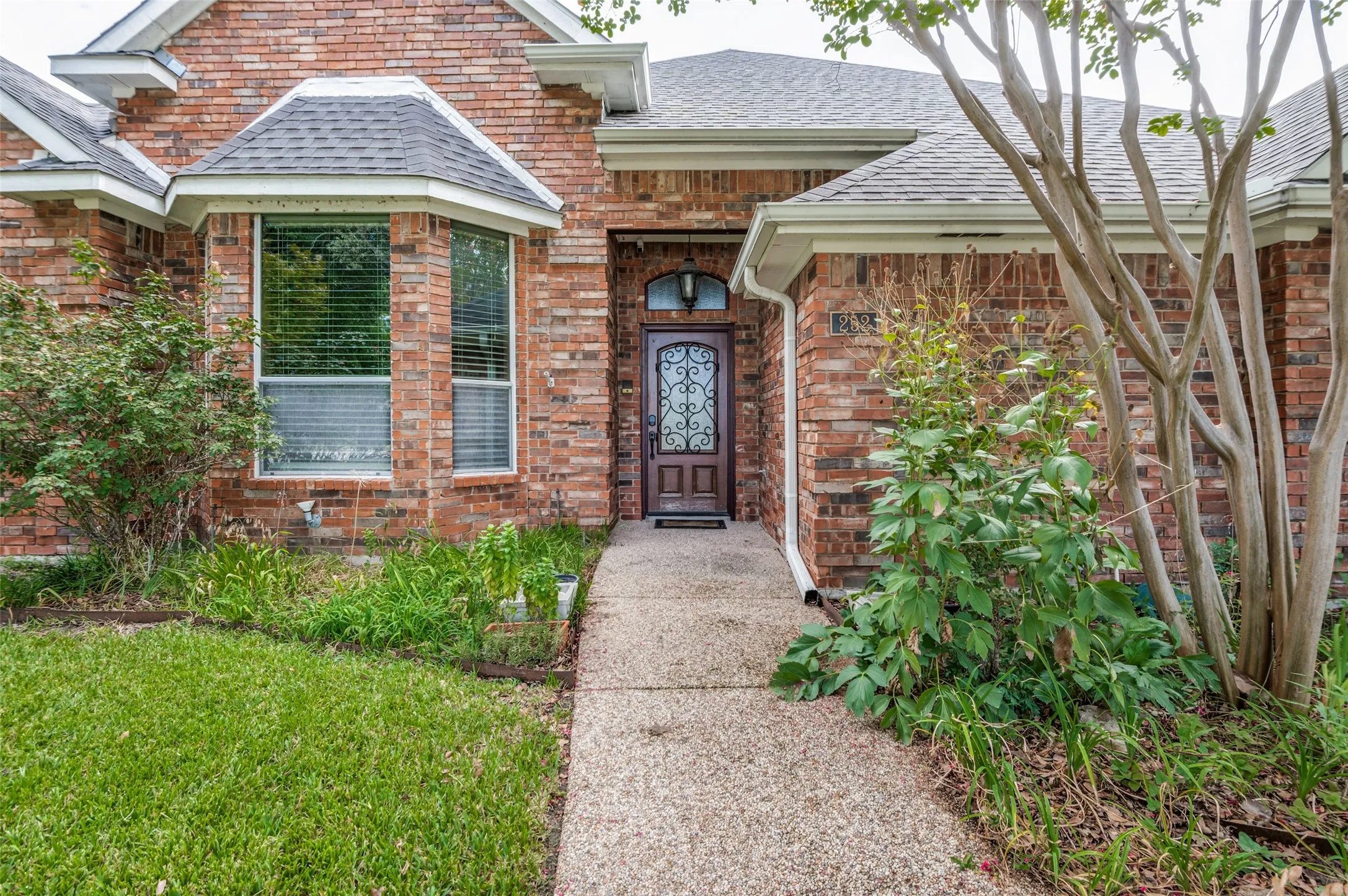 Brick exterior with a covered entry, decorative front door, and bay window