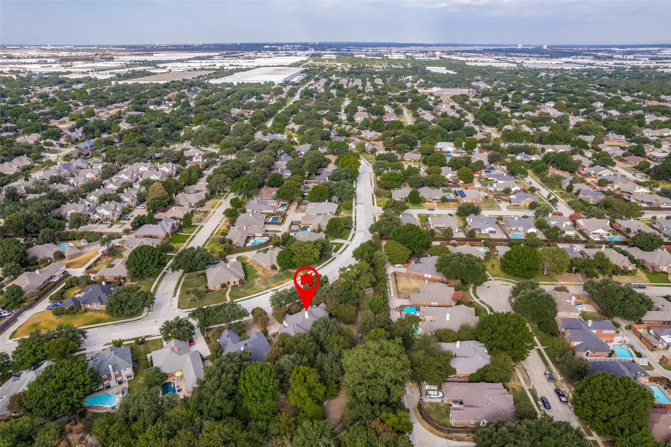 Aerial perspective of a residential neighborhood featuring numerous mature trees and a curvilinear street layout
