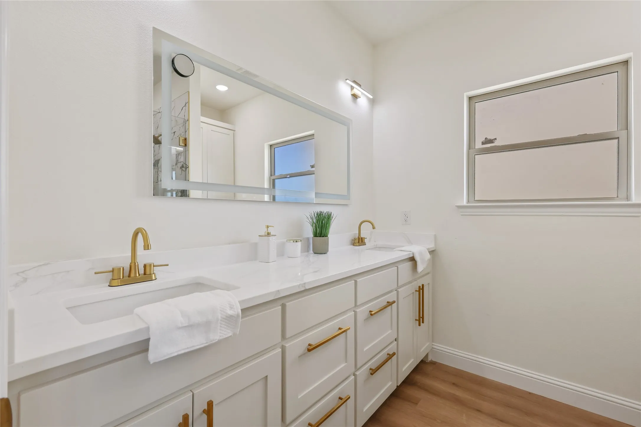 Double vanity with white cabinetry and gold-toned hardware