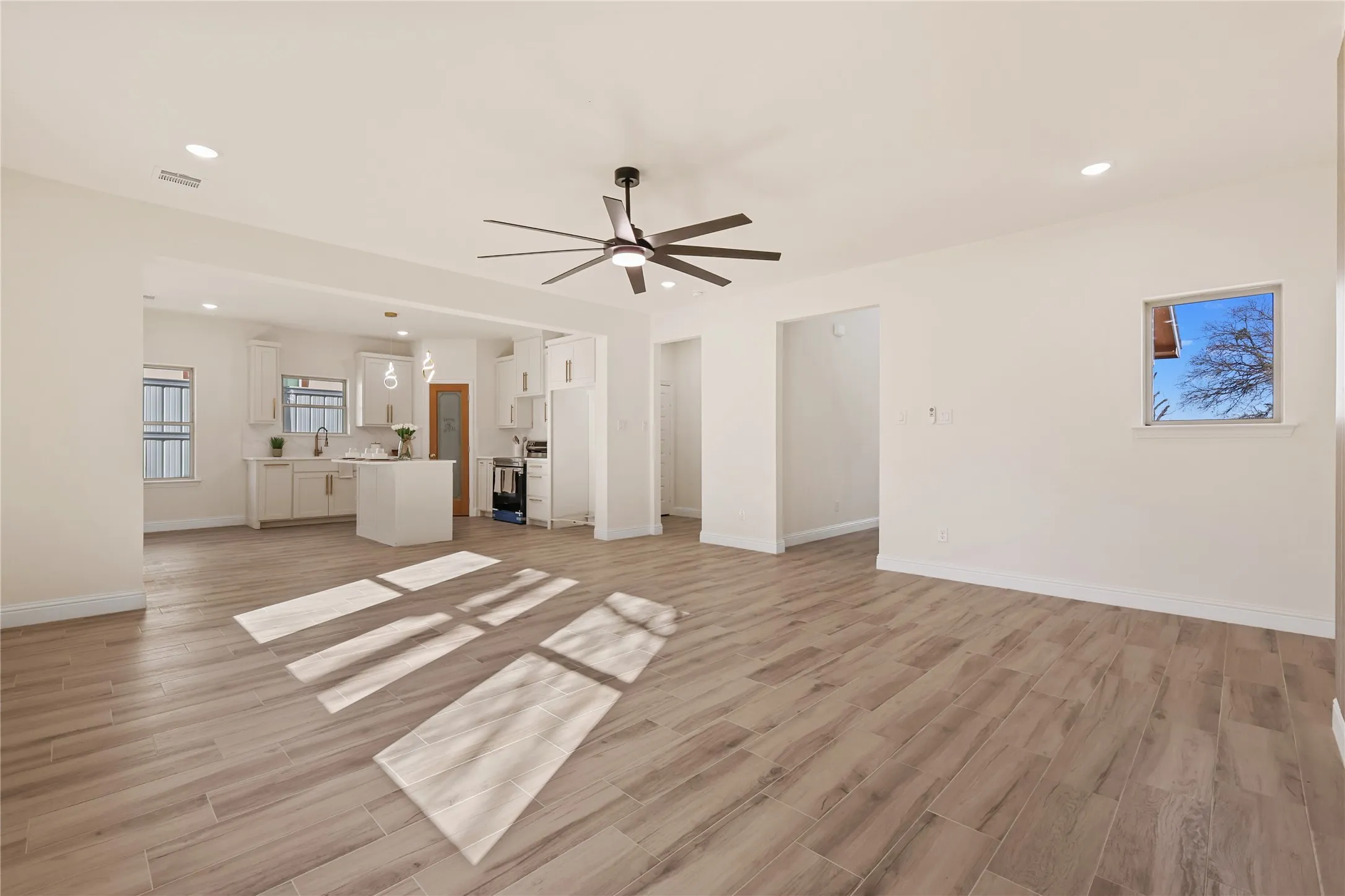Open-concept living area featuring wood-finish flooring, recessed lighting, and a modern ceiling fan