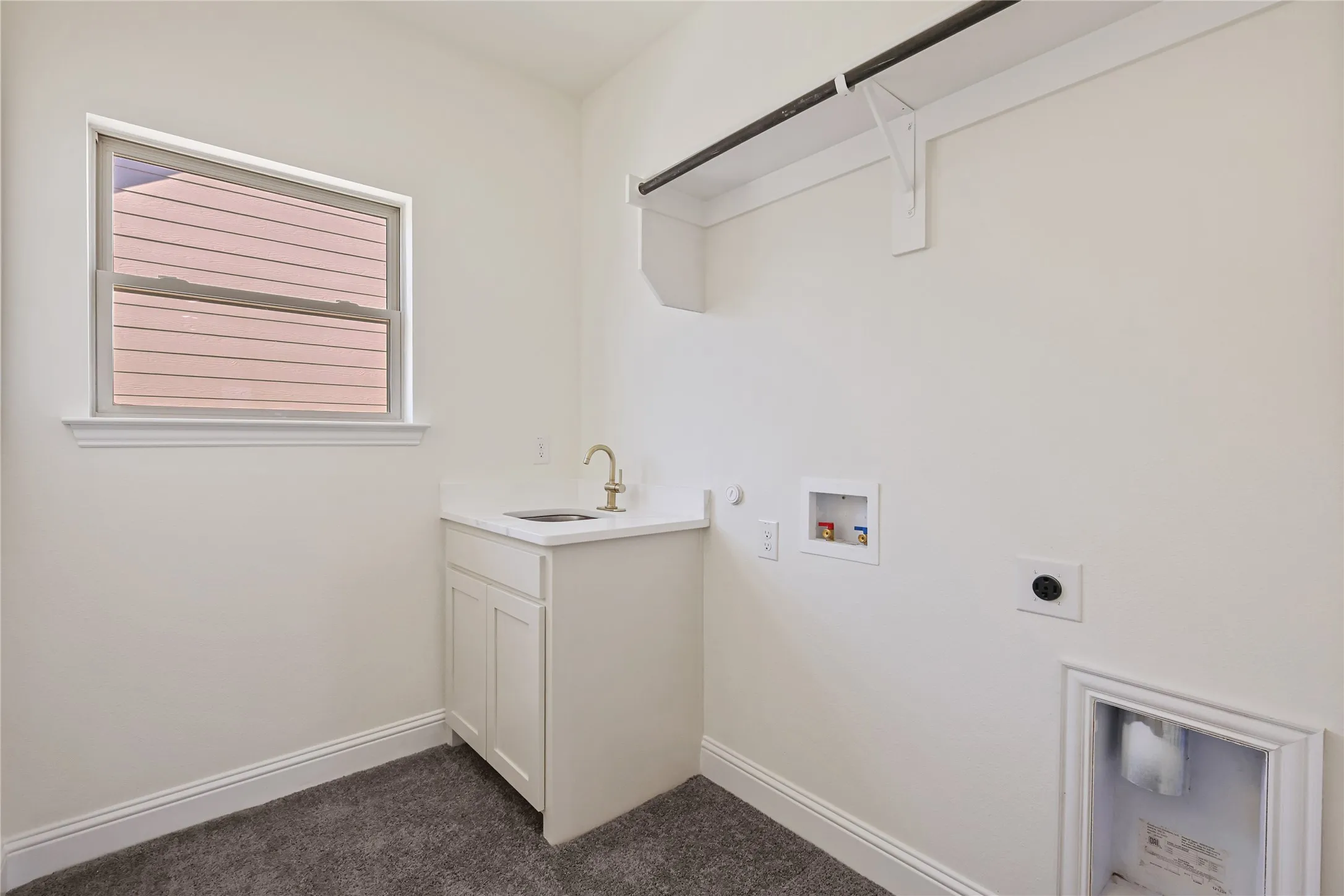 Built-in sink with gold-finish faucet, white cabinetry, and a window