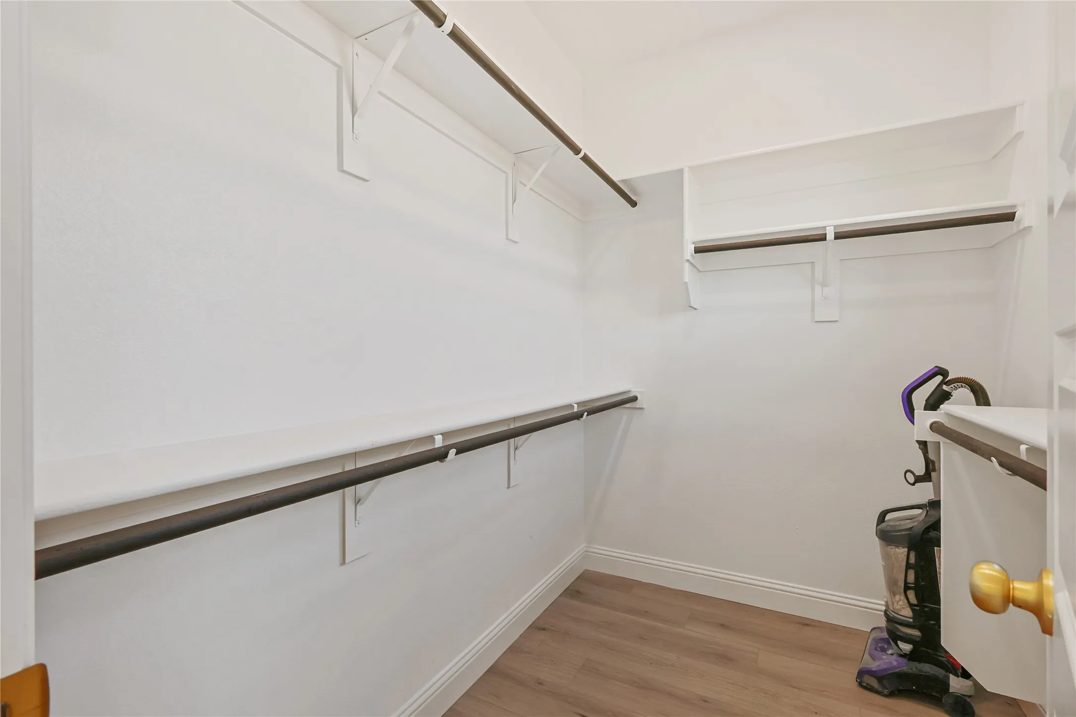 Built-in closet shelving with clothing rods and wood-finish flooring