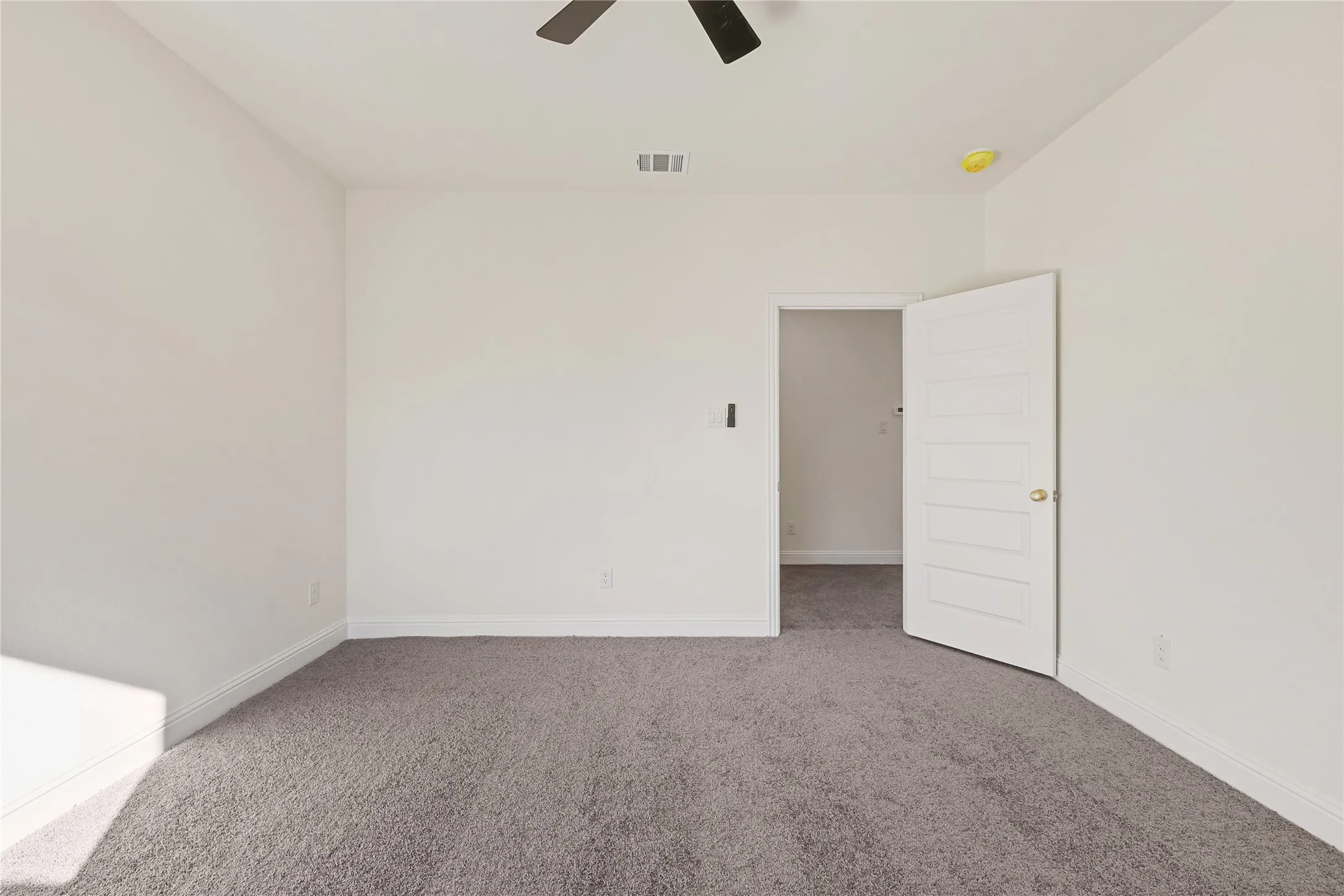 Carpeted flooring, white walls, white trim, and a ceiling fan