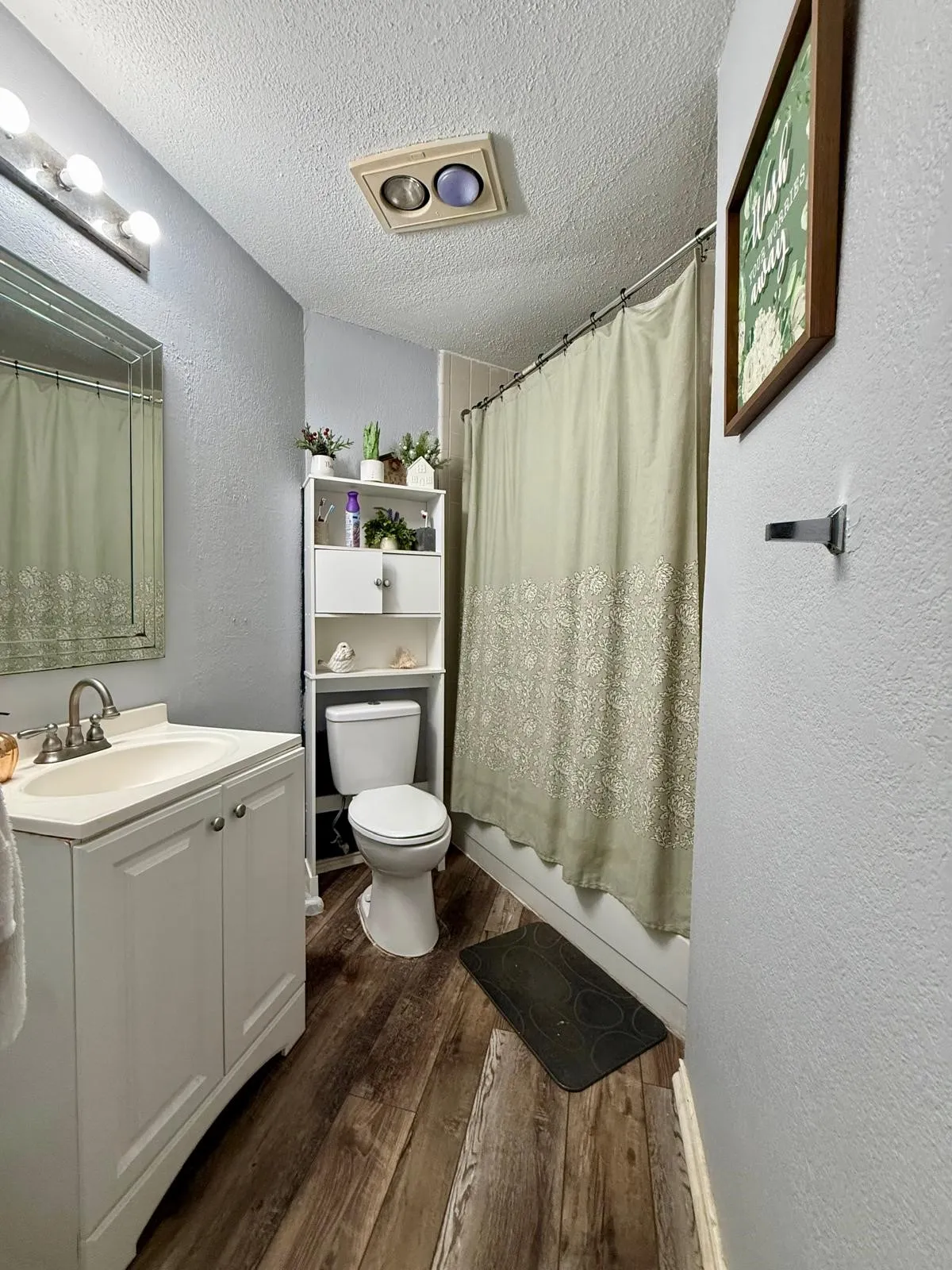 White vanity with a single basin sink, brushed nickel faucet, and wood-finish flooring