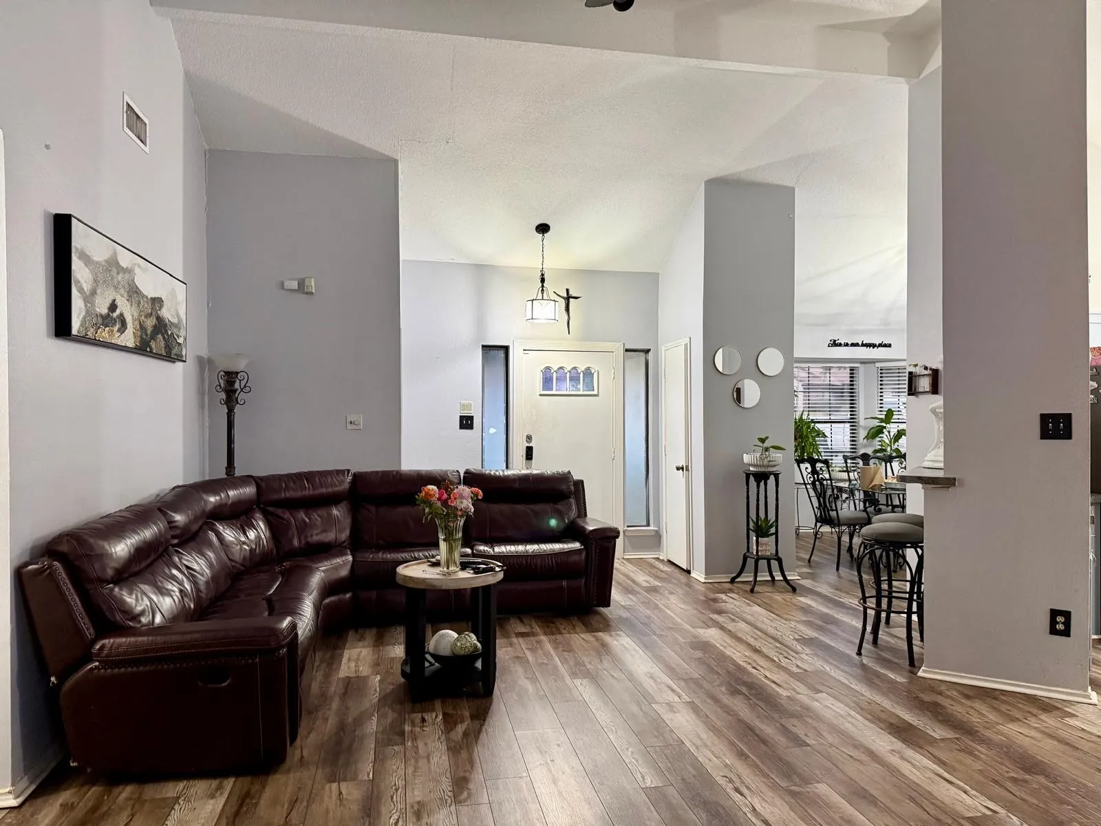 Vaulted ceiling, wood-finish flooring, and a paneled entry door with frosted glass detailing